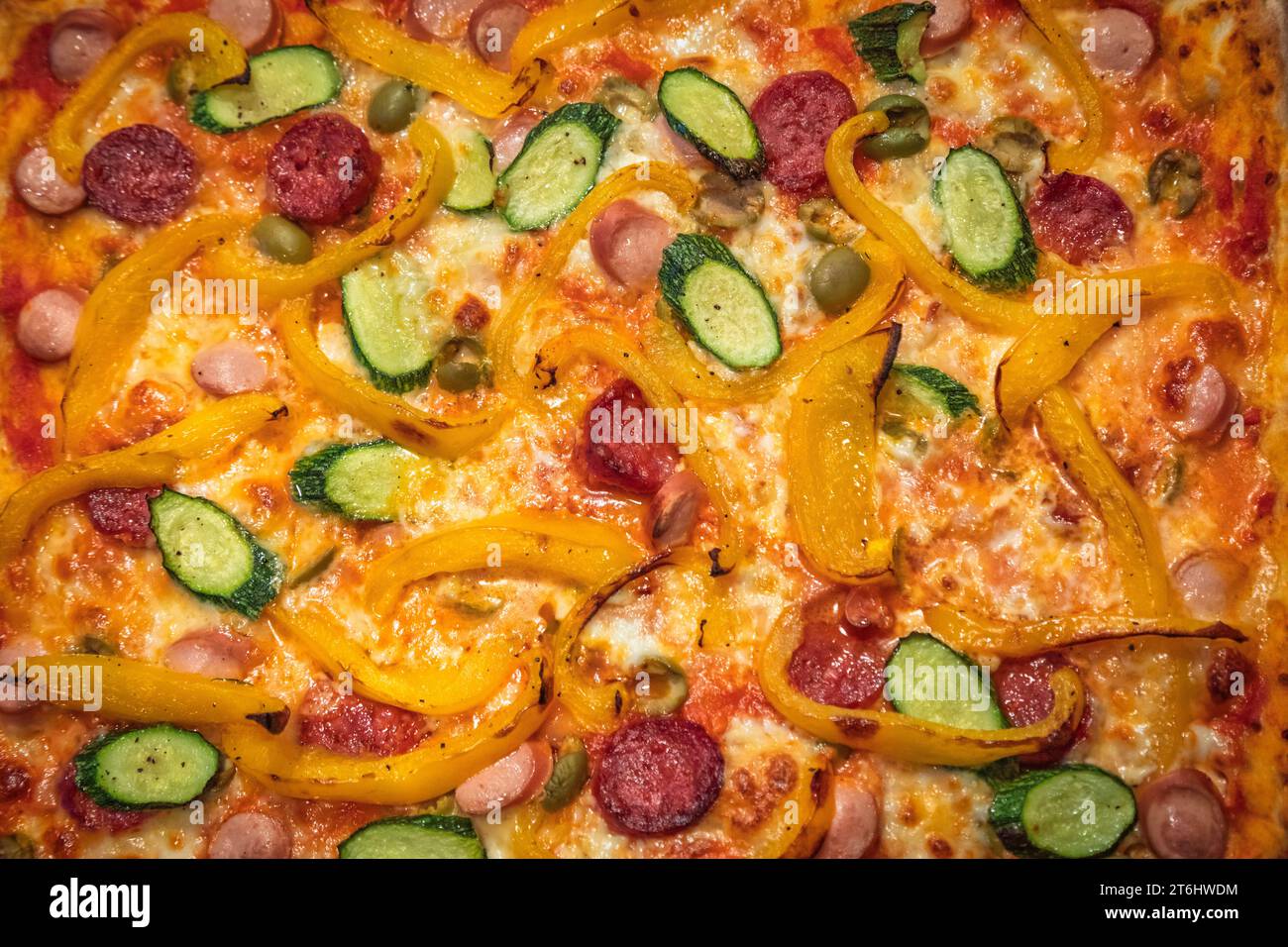 Hausgemachte italienische Pizza gefüllt mit Tomaten, Mozzarella, Paprika, Zucchini, Frankfurts und scharfer Salami Stockfoto