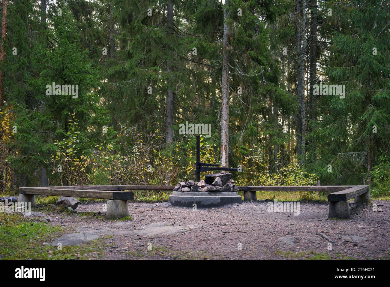 Leerer Lagerfeuerplatz mit Holzbänken und Betonfeuerstelle, Seitenansicht. Hollola, Finnland. Stockfoto