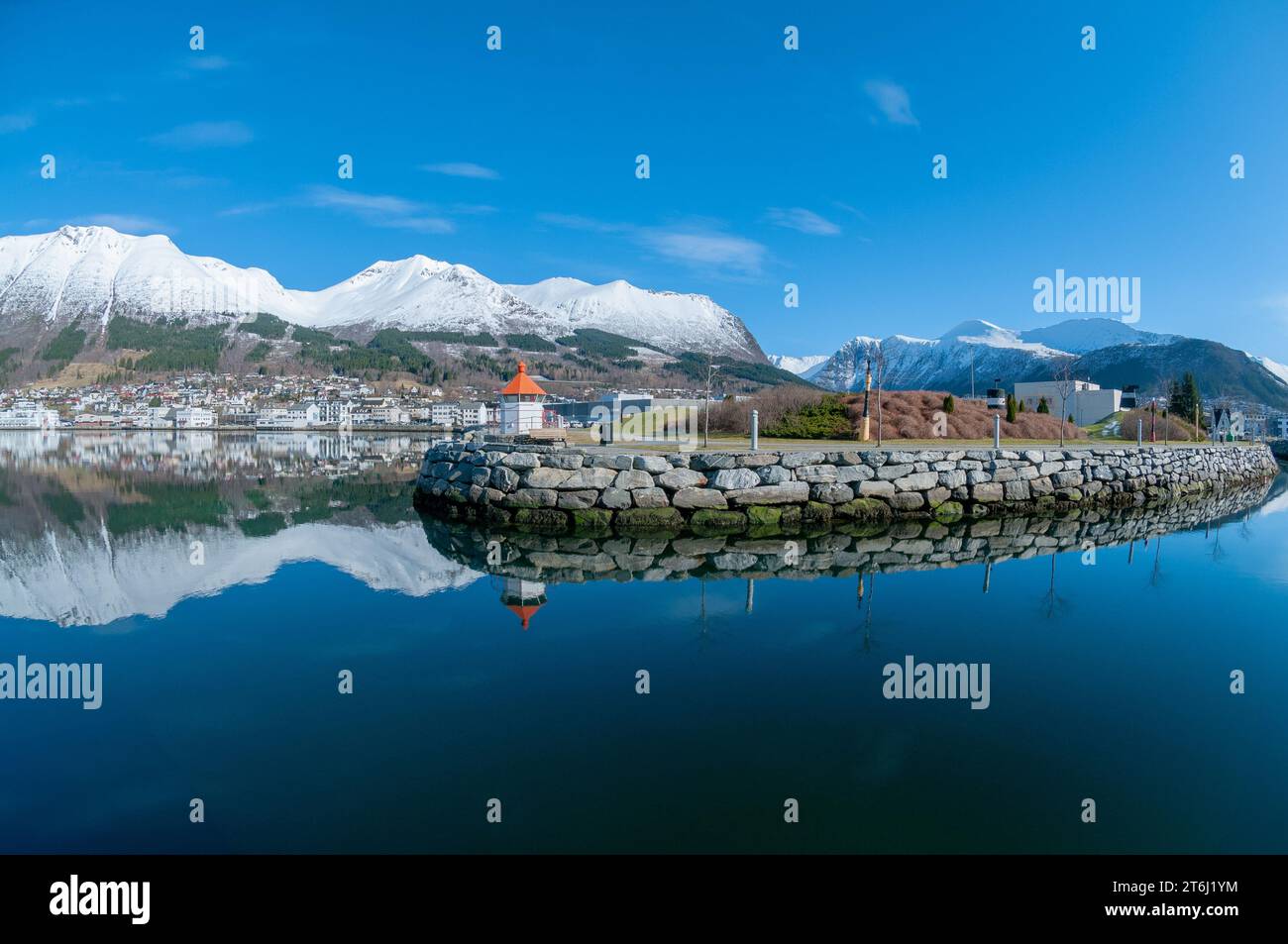 Ein ruhiges Gewässer mit einer majestätischen Steinmauer und Snowy Mountains Stockfoto