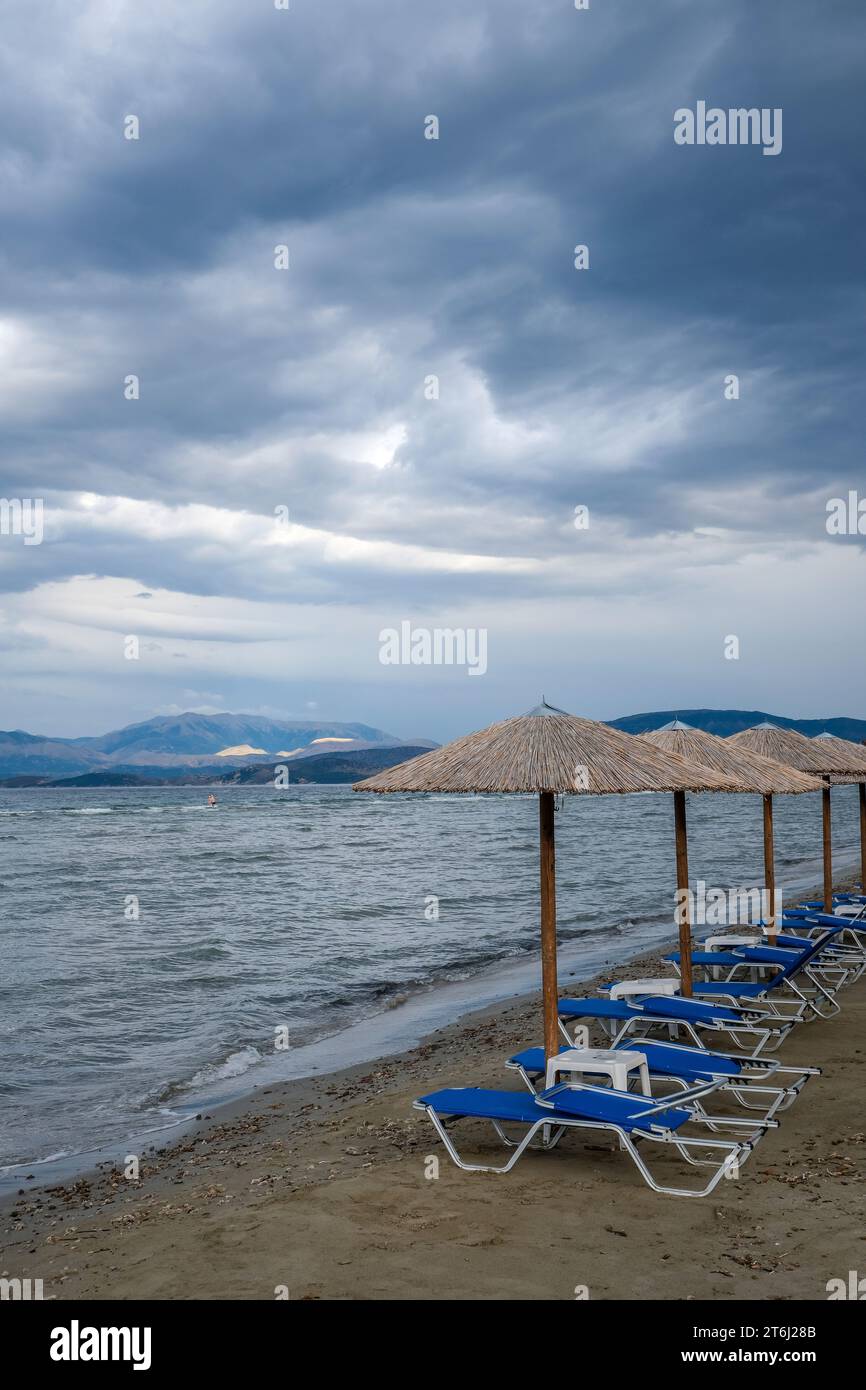 Kalamaki, Korfu, Griechenland, Sonnenliegen und Sonnenschirme am Kalamaki Strand im Nordosten der griechischen Insel Korfu, im Hintergrund das Festland Albaniens Stockfoto