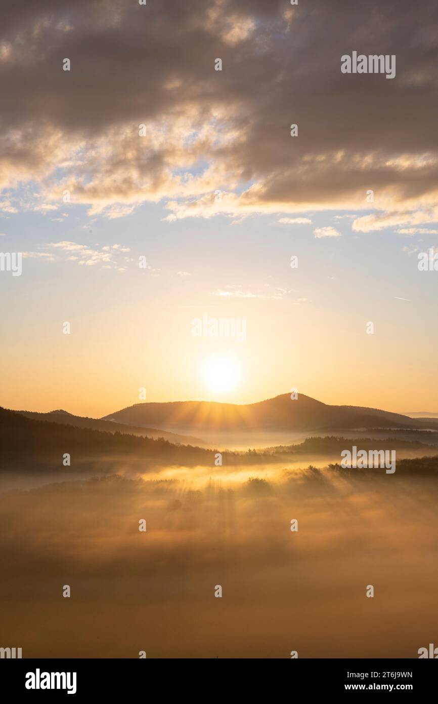 Mystischer Sonnenaufgang am Wachtfelsen. Faszinierende Landschaft zwischen Nebel und Wolken in der Nähe von Wernersberg, Pfälzerwald, Deutschland. Stockfoto