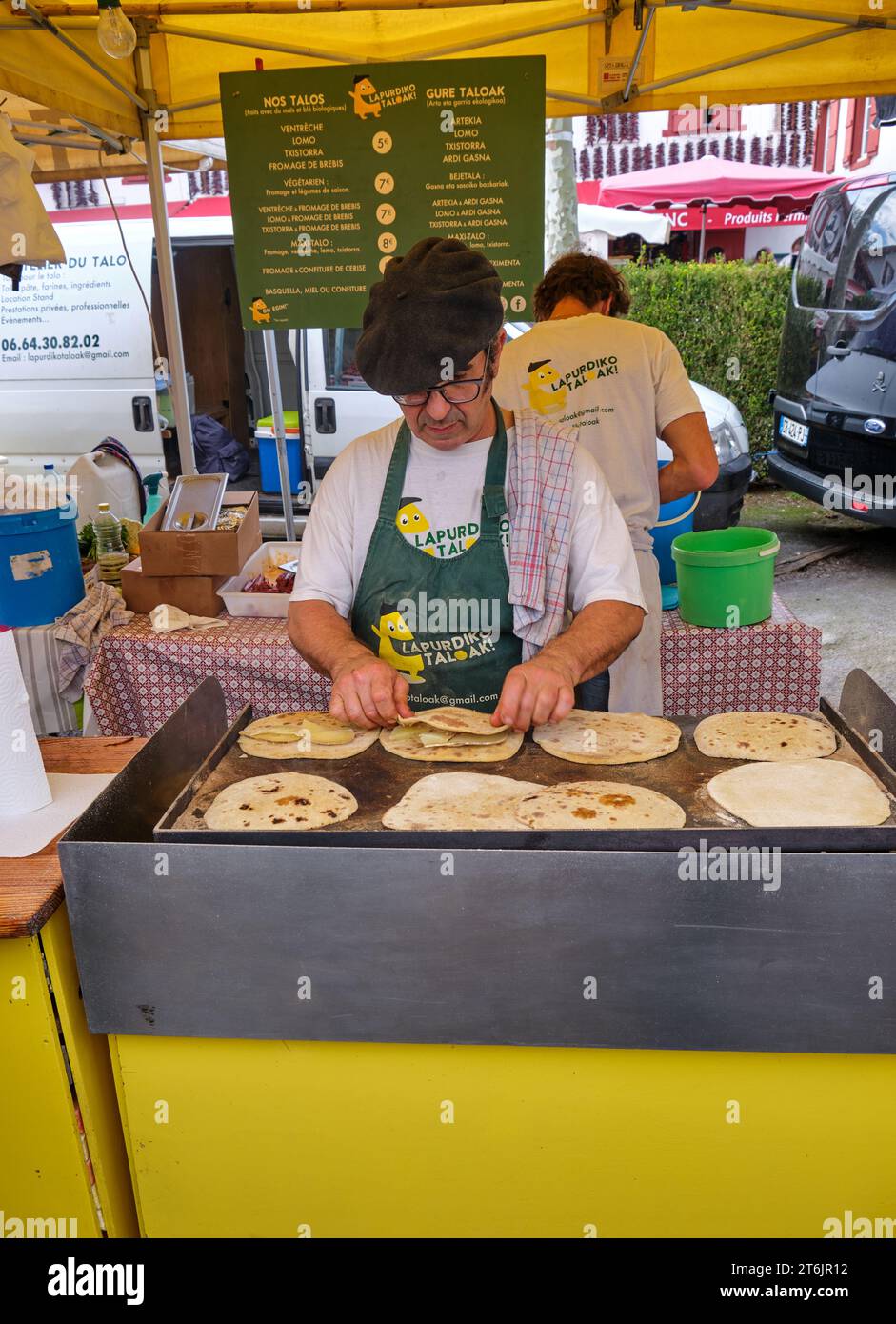 Baskenmann in schwarzer Baskenmütze, der Kuchen auf dem Markt in Espelette, Frankreich, während des jährlichen Pfefferfestivals frittiert Stockfoto