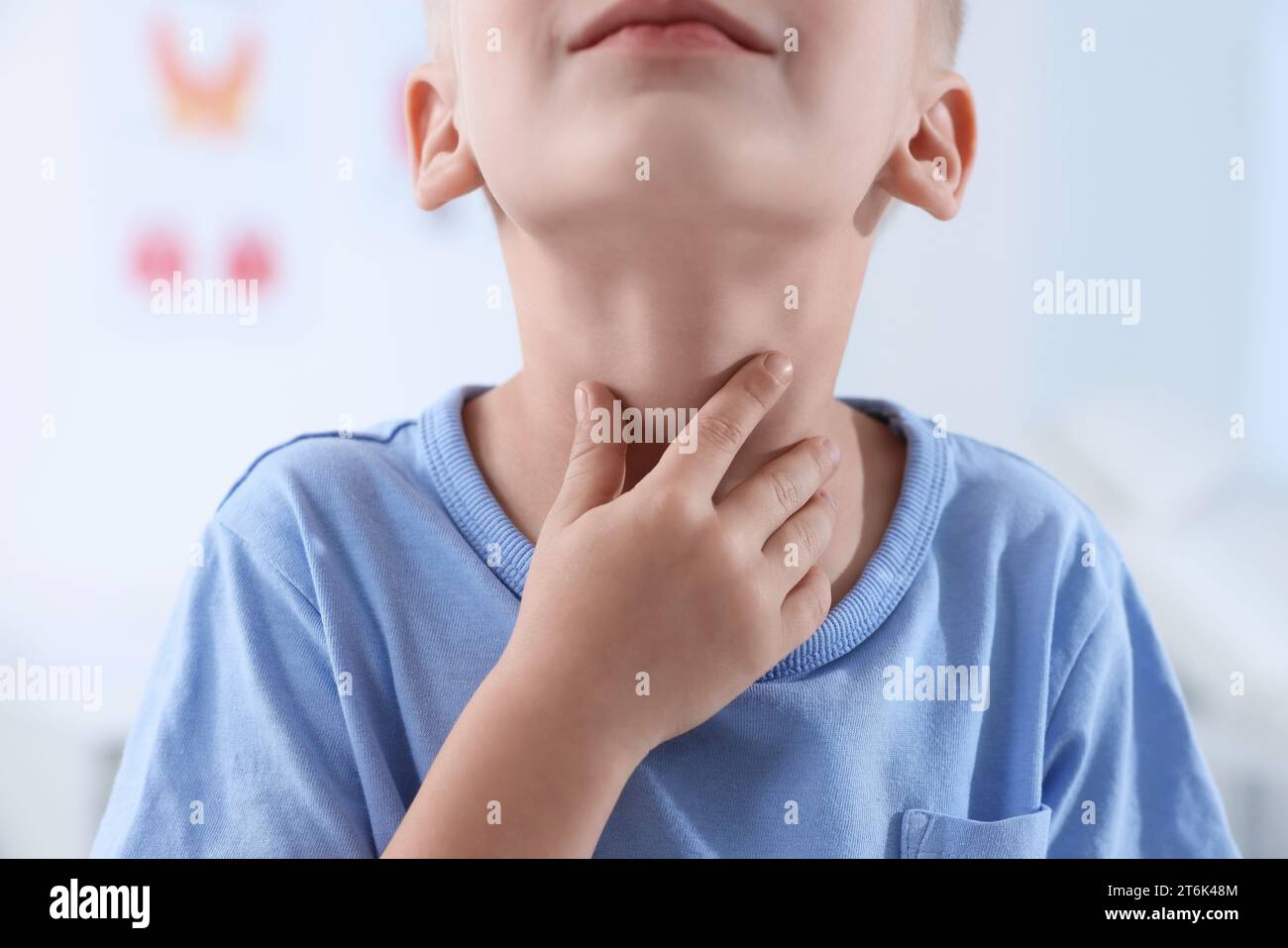 Endokrines System. Kleiner Junge, der drinnen eine Schilddrüsenselbstuntersuchung macht, Nahaufnahme Stockfoto