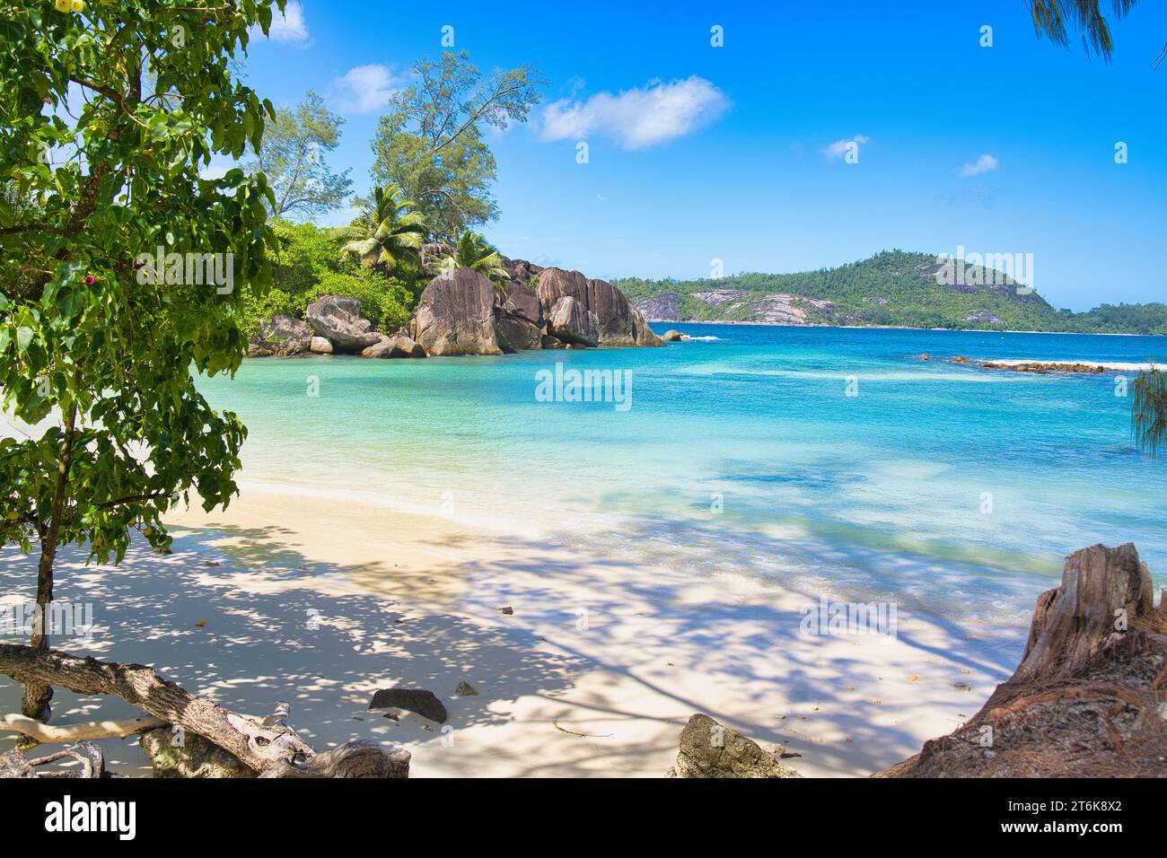 Sonniger, weißer Sandstrand, türkisfarbenes Wasser, Granitsteine am Port glaud Beach, Mahe, Seychellen Stockfoto
