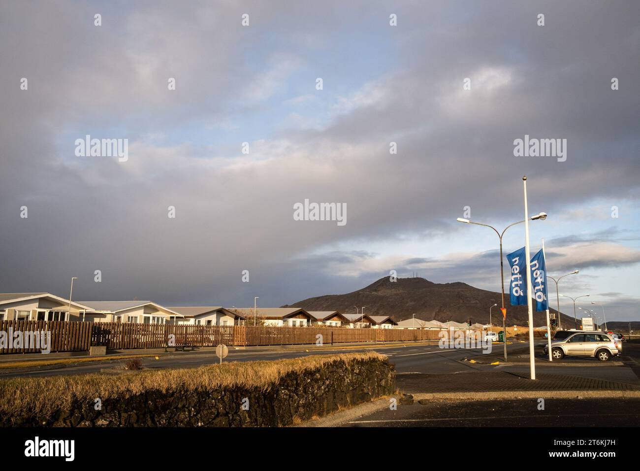 Eine Stadtstraße von Grindavik mit dem Thorbjöm-Berg im Hintergrund. Island bereitet sich auf einen weiteren Vulkanausbruch auf der Halbinsel Reykjanes vor. Nach mehr als 1400 Erdbeben in den letzten 48 Stunden im Gebiet von Grindavik warnen Experten vor einem sehr wahrscheinlichen Vulkanausbruch in den kommenden Tagen. In den Jahren 2021, 2022 und 2023 ereigneten sich in der Nähe des Grindavik-Gebiets, in dem etwa 3200 Menschen lebten. Derzeit hat das bekannte Thermalbad der Blauen Lagune seine Pforten geschlossen, da sich dort eine Vulkanspalte öffnen könnte. Stockfoto