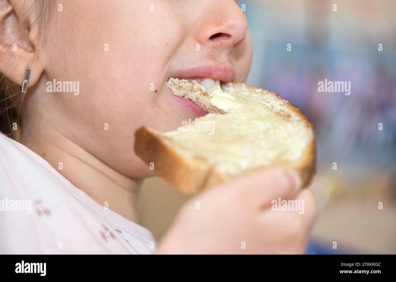 Nahaufnahme eines Mundes eines kaukasischen kleinen Kindes, das Brot und Honig isst Stockfoto