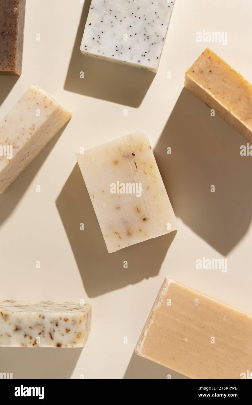 Natürliche, von Hand gefertigte Seifenriegel in Kräutern in Beige und Braun auf hellbeigem Blick von oben, harte Schatten. Hygieneprodukte für Spa und Hautpflege. Mit organischer Handma Stockfoto