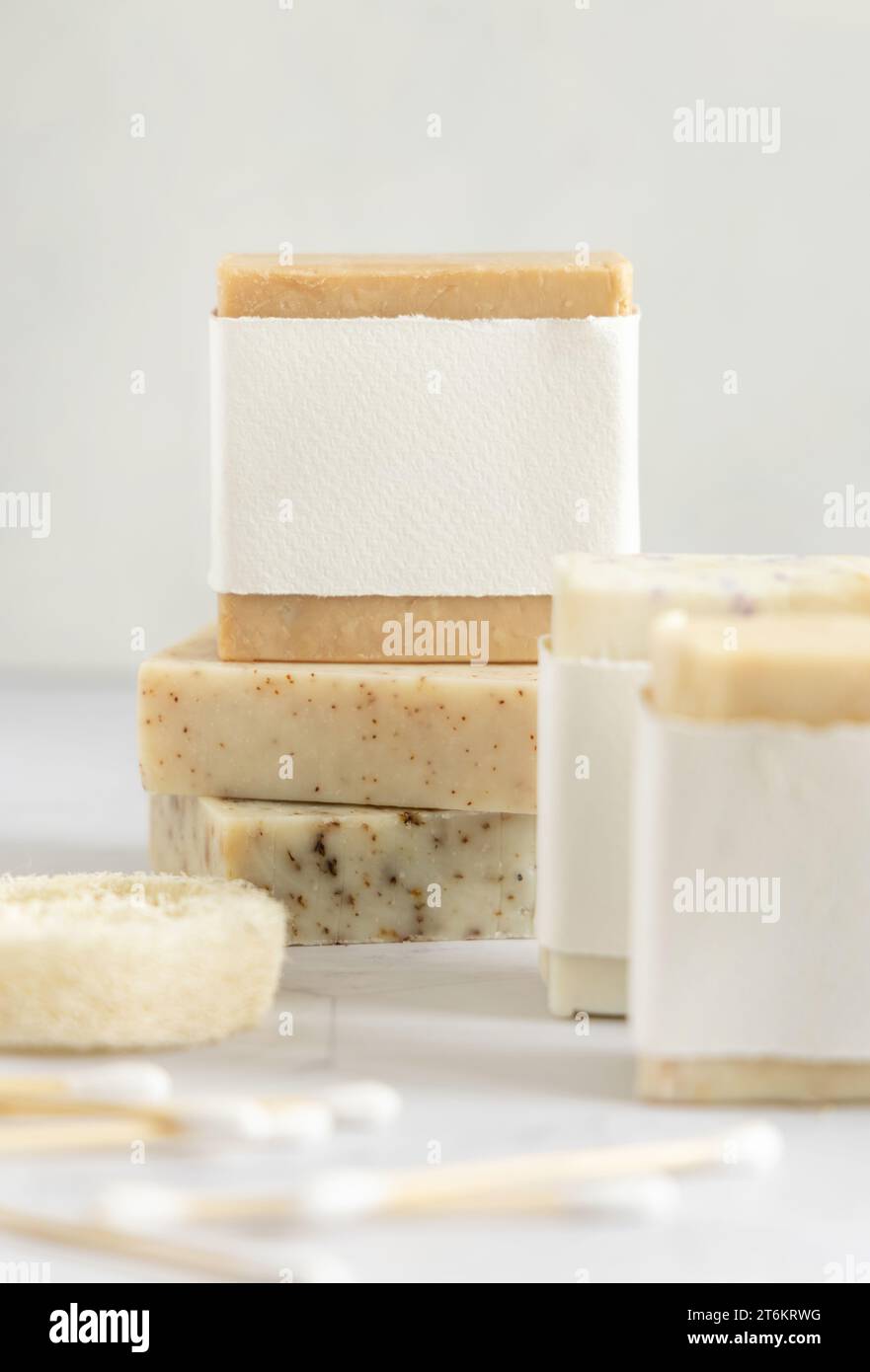 Beige handgemachte Seifenstange mit leerem Etikett auf Marmortisch in der Nähe von natürlichem Luffa Schwamm Nahaufnahme, Mockup, Kopierraum. Natürliche pflanzliche Produkte für Gesicht und Stockfoto