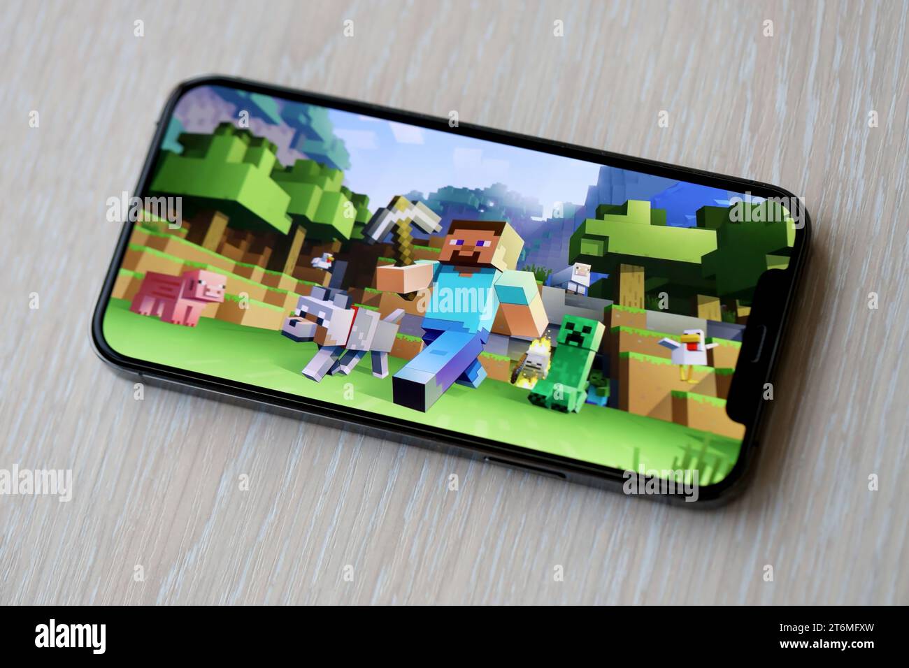 Minecraft mobiles iOS-Spiel auf dem iPhone 15 Smartphone-Bildschirm auf Holztisch während des mobilen Gameplays. Mobiles Gaming und Entertainment auf einem tragbaren Gerät Stockfoto