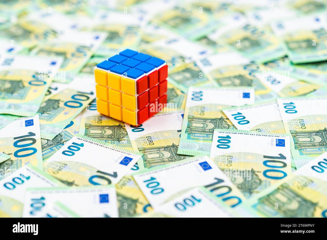 rubik-Würfel bei vielen Euro-Banknoten gelöst, 100-Euro-Geldscheine, Entscheidungskonzept. Hochwertige Fotos Stockfoto