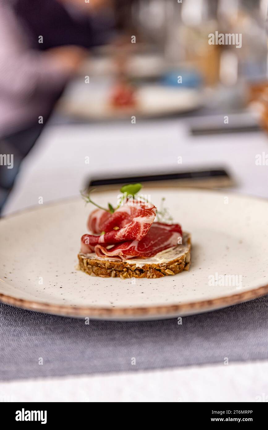 Prosciutto elegant auf einem mit Grün garnierten Brot angeordnet, was seine optische Anziehungskraft unterstreicht. Stockfoto
