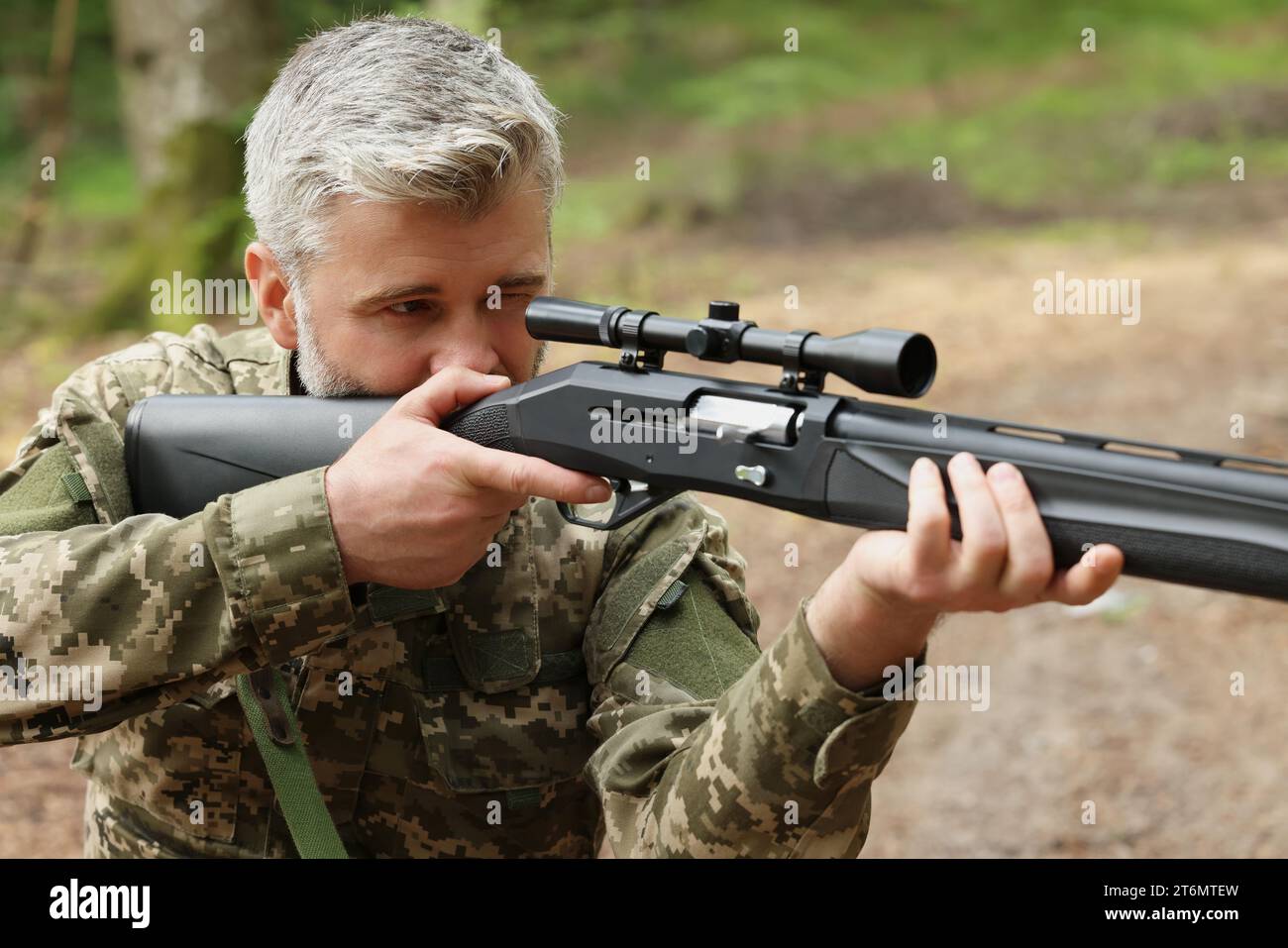 Mann, der mit Jagdgewehr im Wald zielt Stockfoto