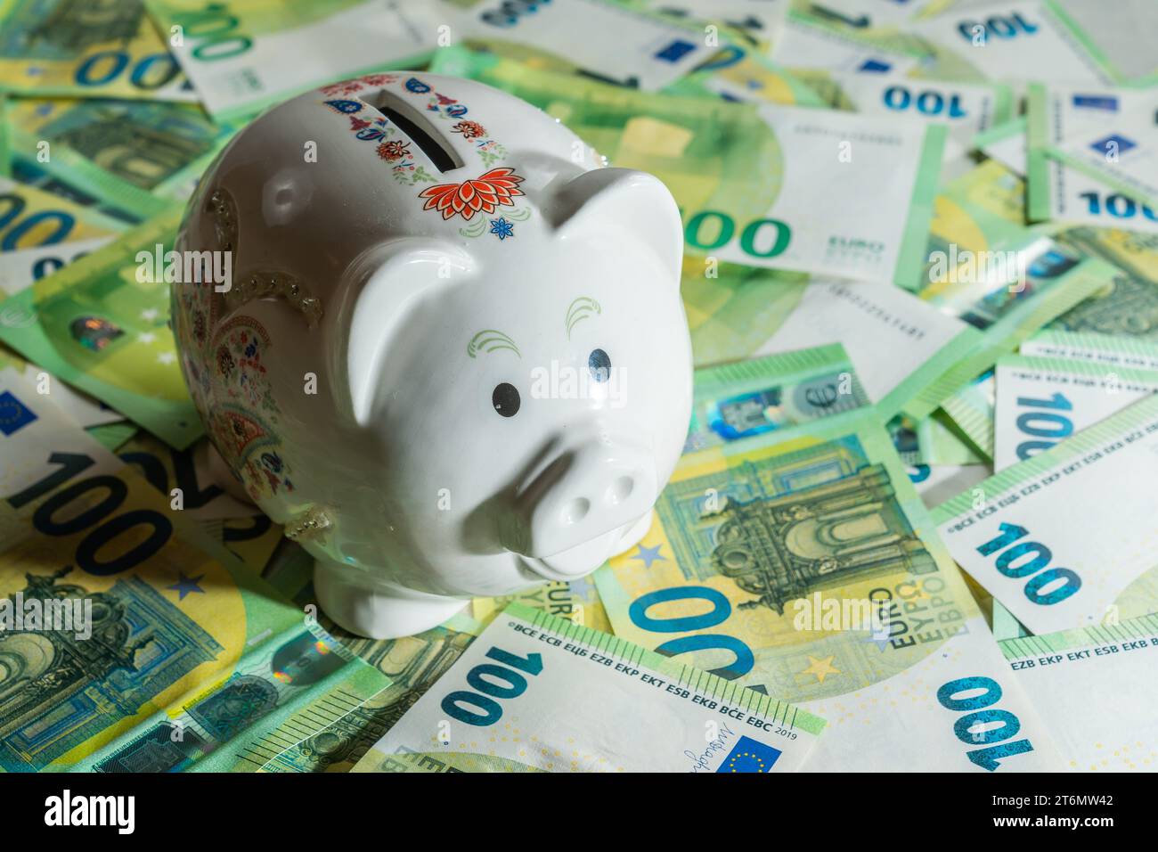 Geldschwein auf dem Hintergrund von Geldrechnungen von 100 Euro, c linker Blick auf Schweinebank Nahaufnahme. Hochwertige Fotos Stockfoto