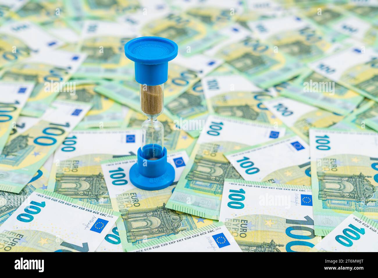 Sanduhr auf dem Hintergrund vieler Banknoten, Euro-Geldscheine, 100 Euro. Konzepte von Investitionen, Rentengeld und Geldbewegung. Hohe Qualität Stockfoto