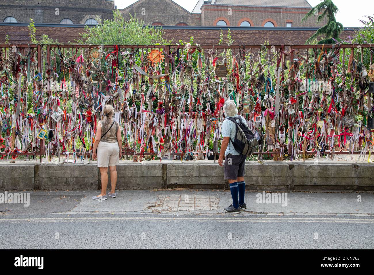 Zwei Personen halten an und schauen sich die Bänder und Nachrichten vor dem Friedhof Crossbones und dem Erinnerungsgarten in London an Stockfoto