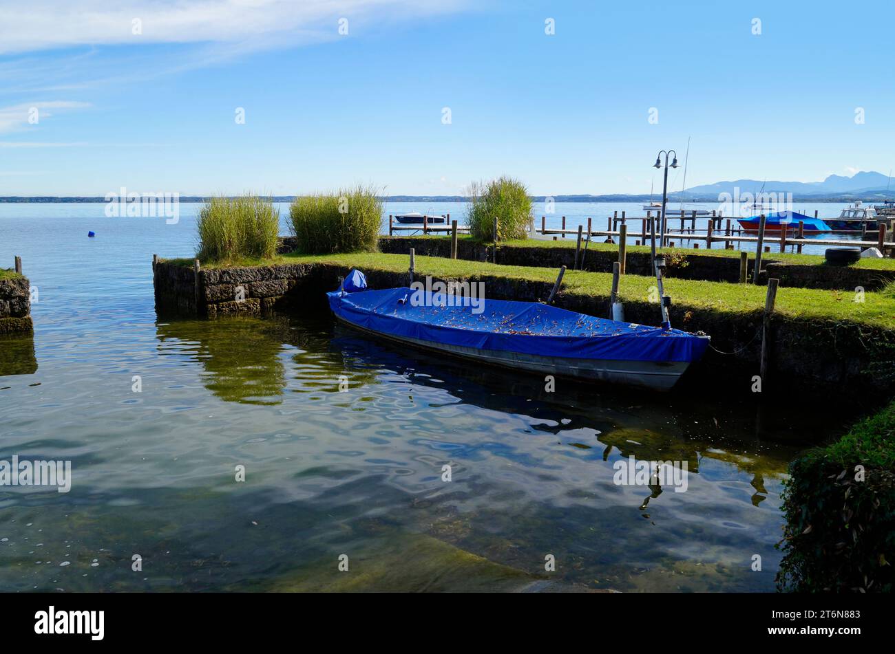 Eine malerische Aussicht mit einem alten Fischerboot auf der Insel Frauenchiemsee oder Fraueninsel auf dem Chiemsee an einem sonnigen Oktobertag in Bayern (Deutschland) Stockfoto