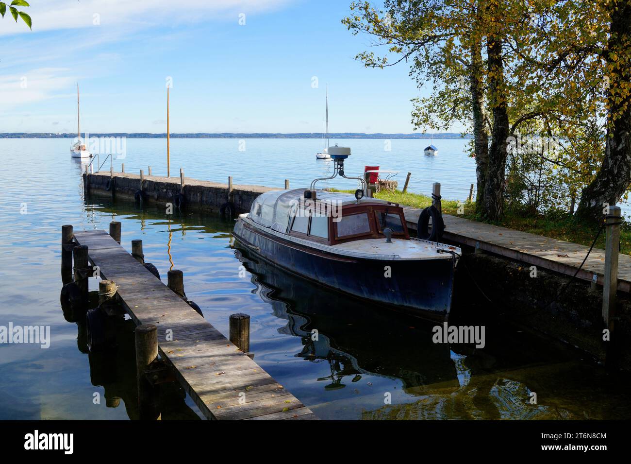 Eine malerische Aussicht mit einem alten Fischerboot auf der Insel Frauenchiemsee oder Fraueninsel auf dem Chiemsee an einem sonnigen Oktobertag in Bayern (Deutschland) Stockfoto