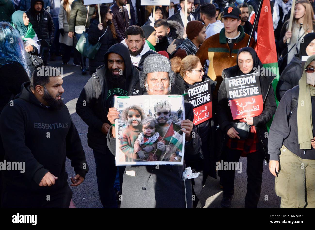 Älterer muslimischer Mann mit Sauerstoffmaske trägt ein Foto von bombardierten palästinensischen Kindern; Szenen aus der Massendemonstration gegen den Krieg pro Waffenstillstand in Zentral-london, die einen Waffenstillstand in palästina israel gaza 11. november 2023 forderte Stockfoto
