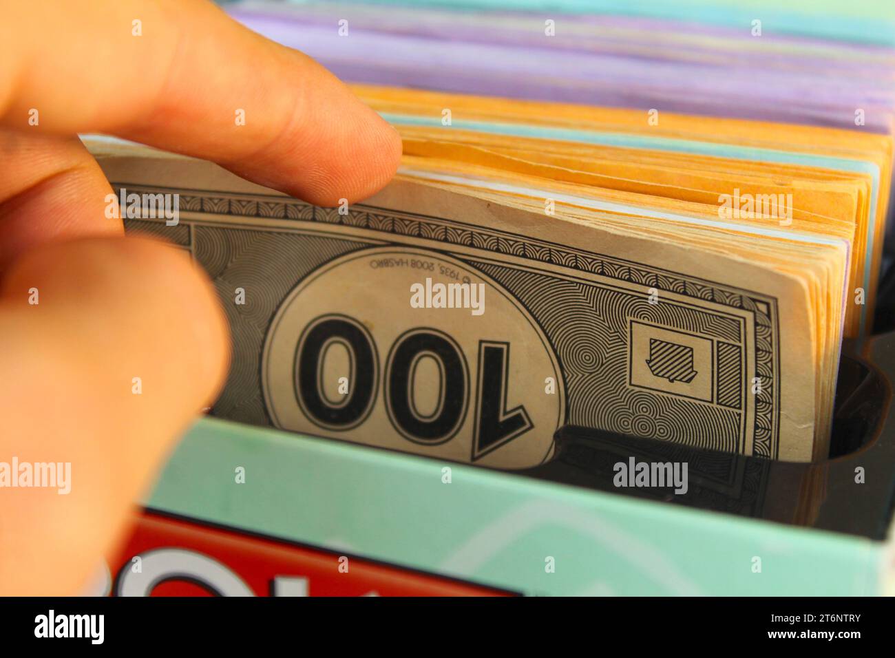 Ein Foto von jemandem, der durch Monopoly-Brettspiel-Papiergeld flippt. Stockfoto