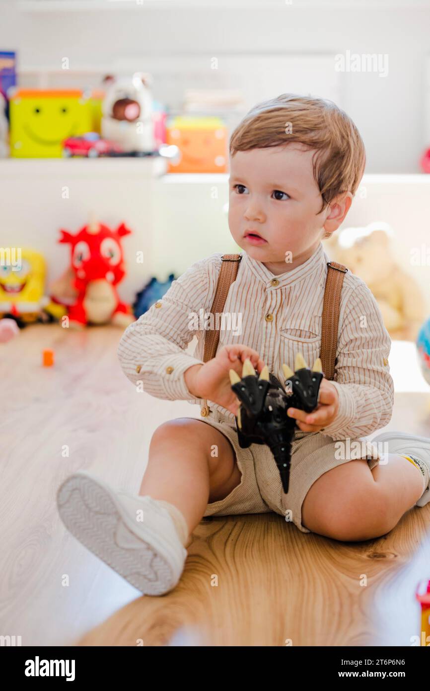 Junge sitzt und spielt mit Dinosaurierspielzeug Stockfoto