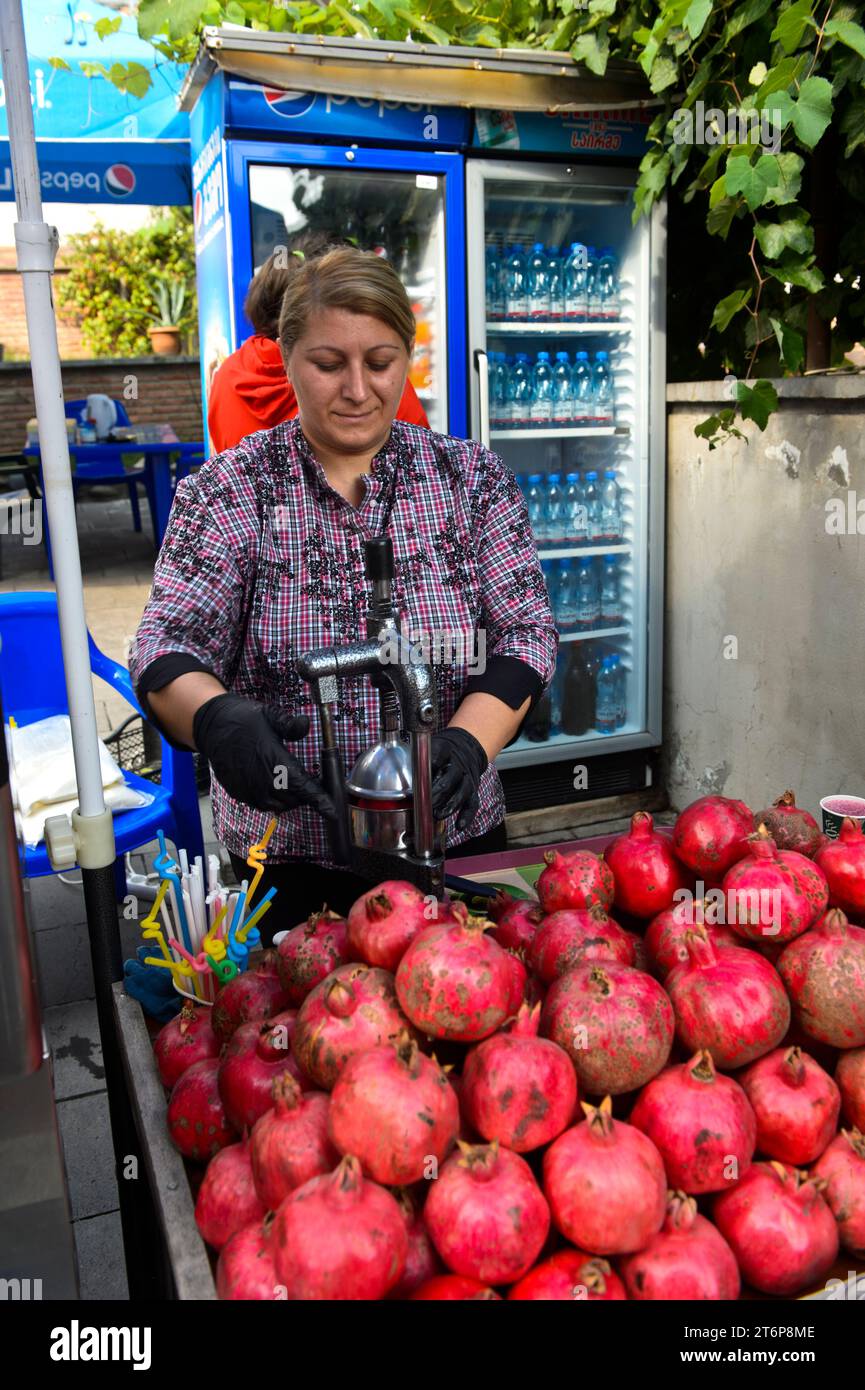 Frau bereitet Saft aus Granatäpfeln (Punica granatum) an einem Stand in der Altstadt von Tiflis, Tblisi, Georgien zu Stockfoto