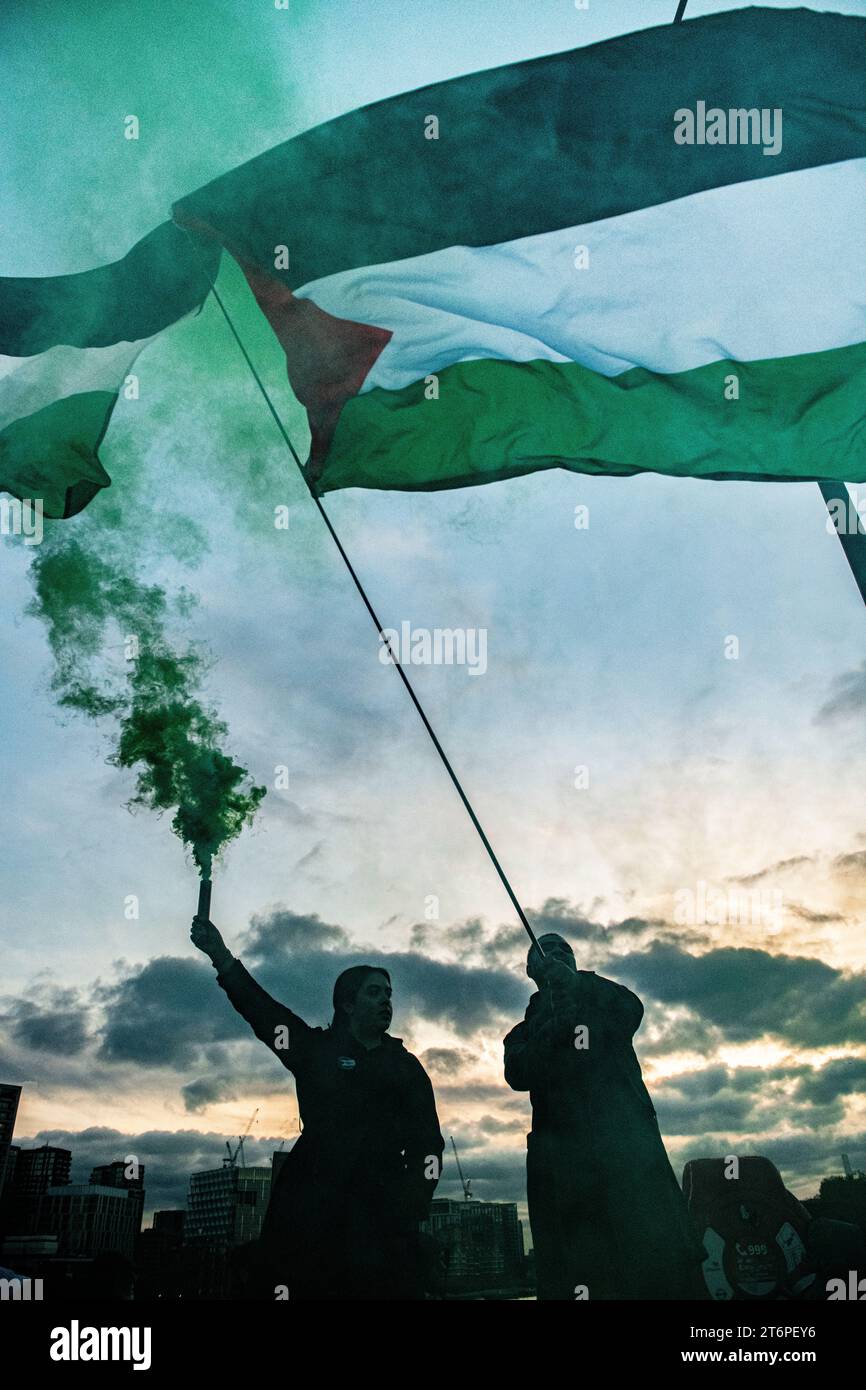 London, Großbritannien. 11. November 2023. In der Abenddämmerung werden Flares auf der Vauxhall Bridge ausgelöst, während palästinensische Anhänger durch London zur US-Botschaft marschieren. Stockfoto