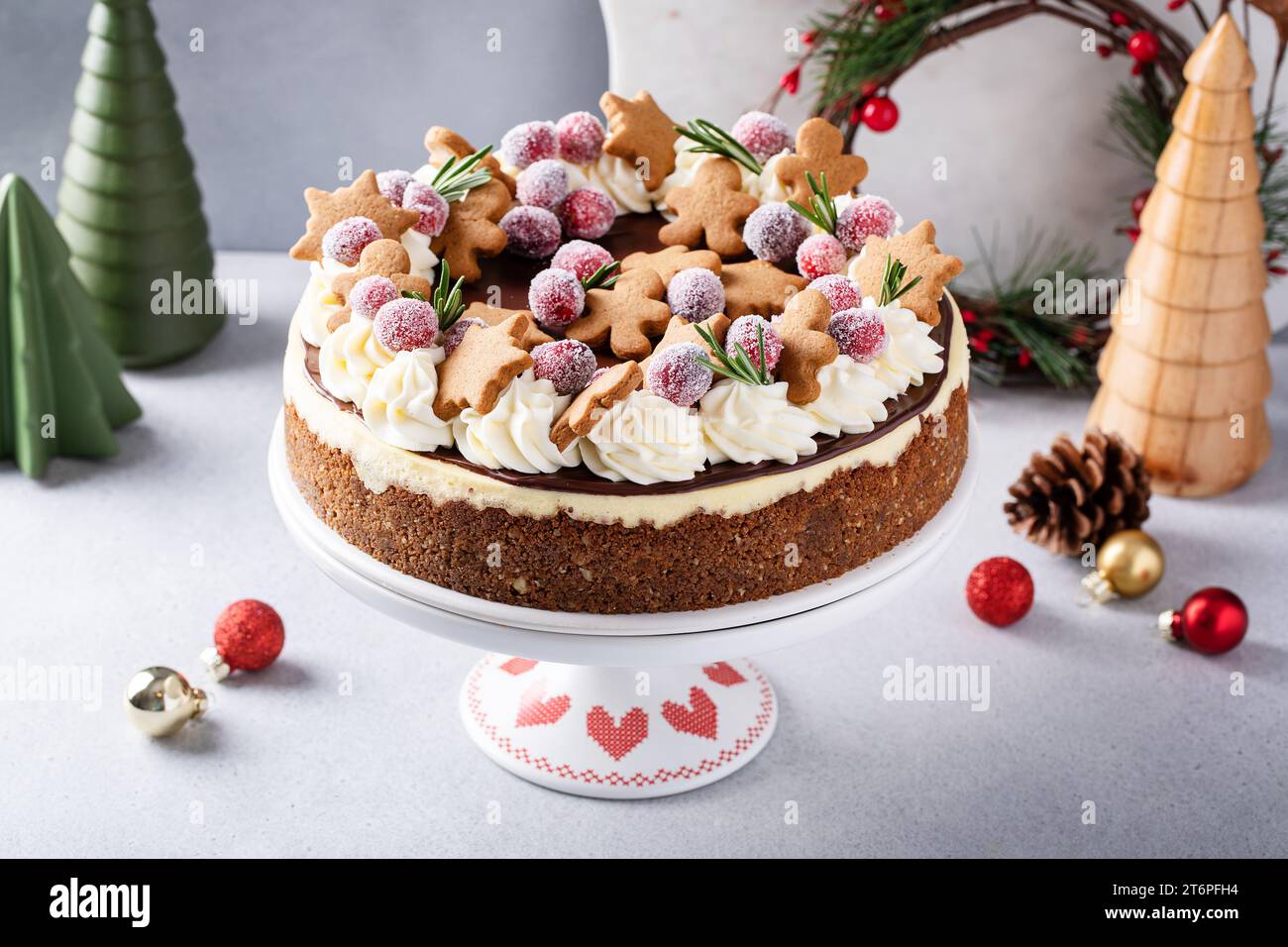 Weihnachtskuchen dekoriert mit Lebkuchenkeksen und gezuckerten Preiselbeeren, festliche Feiertags-Käsekuchen-Idee Stockfoto