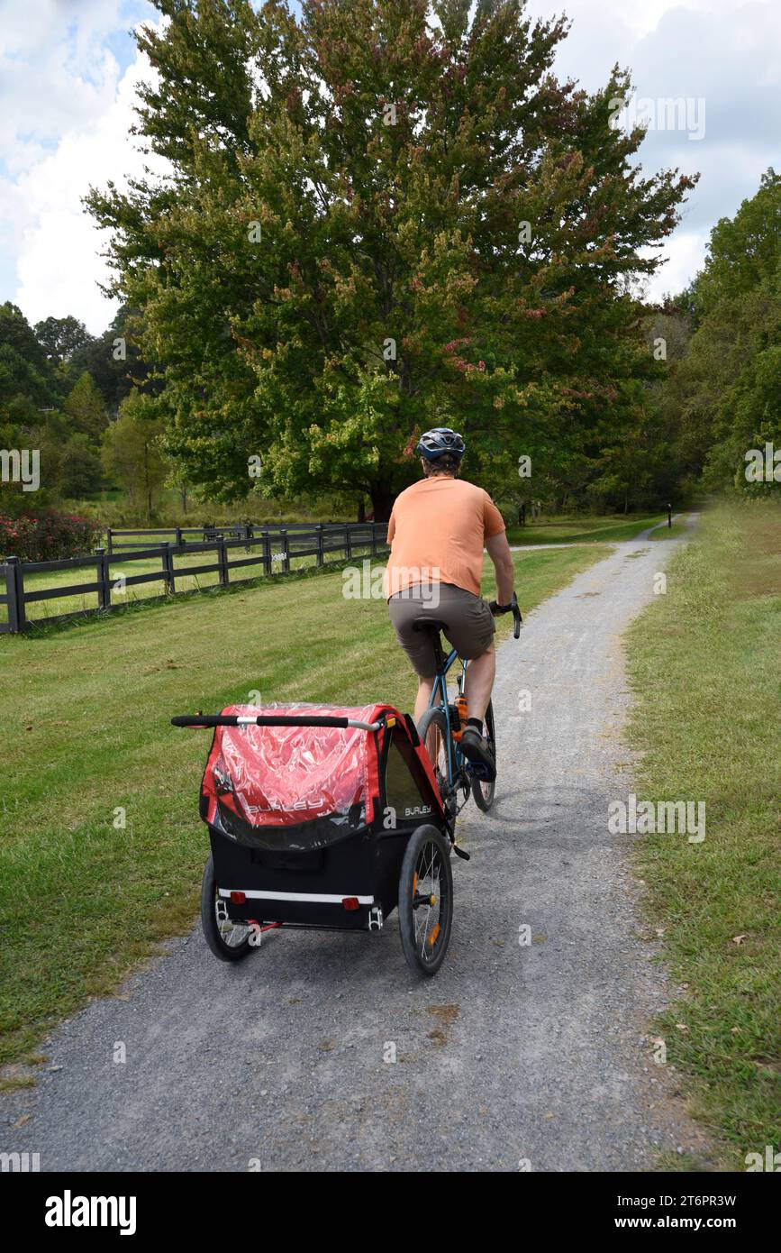 Ein Mann auf einem Fahrrad zieht einen Burley-Anhänger entlang des beliebten Virginia Creeper Trail in Abingdon, Virginia. Stockfoto