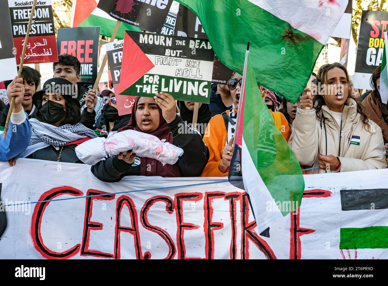 11. November 2023, London, Großbritannien. Hunderttausende von Menschen marschieren durch das Zentrum Londons, um gegen die anhaltende Bombardierung des Gazastreifens durch Israel zu protestieren. Die Organisatoren der Demonstration, der palästinensischen Solidaritätskampagne, fordern einen sofortigen Waffenstillstand. Im Bild: Eine Frau an der Spitze des marsches hält eine symbolische Leiche, die die Toten bei der Bombardierung von Gaza repräsentiert. Stockfoto