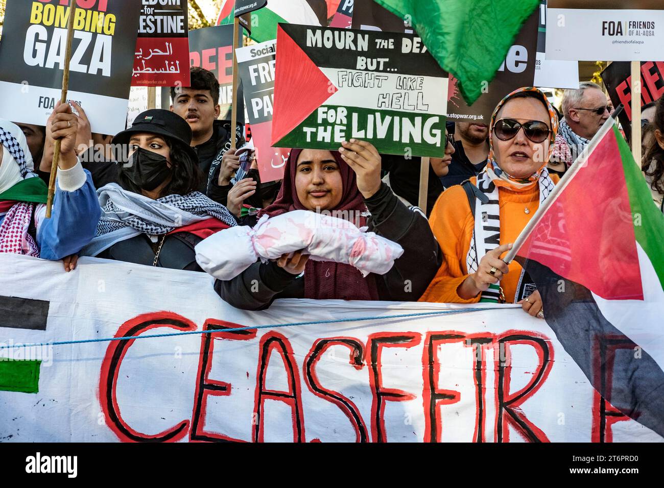 11. November 2023, London, Großbritannien. Hunderttausende von Menschen marschieren durch das Zentrum Londons, um gegen die anhaltende Bombardierung des Gazastreifens durch Israel zu protestieren. Die Organisatoren der Demonstration, der palästinensischen Solidaritätskampagne, fordern einen sofortigen Waffenstillstand. Im Bild: Eine Frau an der Spitze des marsches hält eine symbolische Leiche, die die Toten bei der Bombardierung von Gaza repräsentiert. Stockfoto