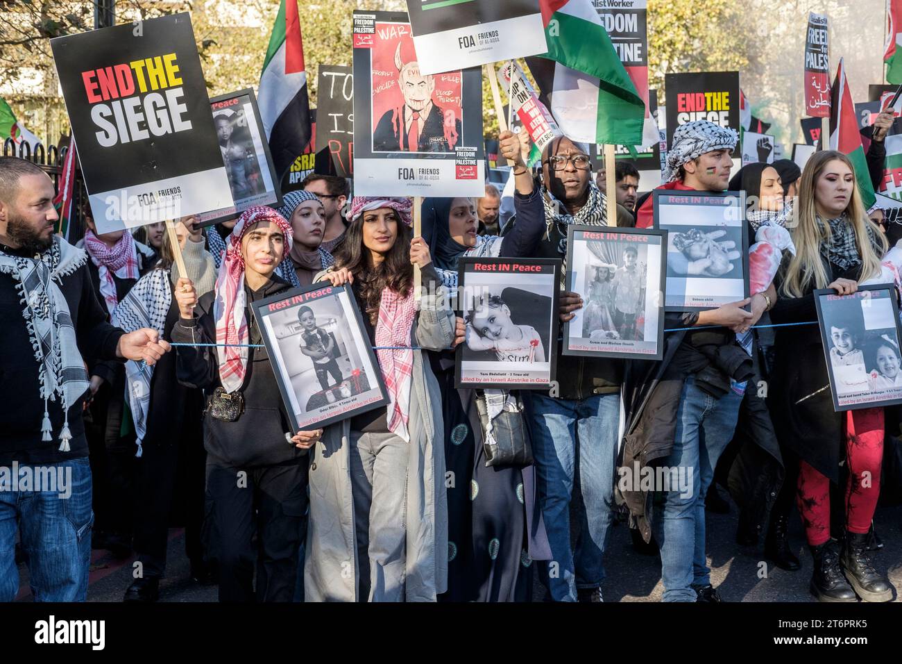 11. November 2023, London, Großbritannien. Hunderttausende von Menschen marschieren durch das Zentrum Londons, um gegen die anhaltende Bombardierung des Gazastreifens durch Israel zu protestieren. Die Organisatoren der Demonstration, der palästinensischen Solidaritätskampagne, fordern einen sofortigen Waffenstillstand. Im Bild: Demonstranten zeigen Fotos von Kindern, die durch den israelischen Bombardement auf Gaza getötet wurden. Stockfoto