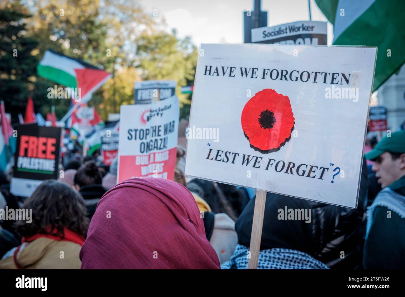 11. November 2023, London, Großbritannien. Hunderttausende von Menschen marschieren durch das Zentrum Londons, um gegen die anhaltende Bombardierung des Gazastreifens durch Israel zu protestieren. Die Organisatoren der Demonstration, der palästinensischen Solidaritätskampagne, fordern einen sofortigen Waffenstillstand. Im Bild: Ein Plakat mit einem Mohnbild, das die Worte Lest We Forget hinterfragt, wird entlang der Route getragen. Stockfoto