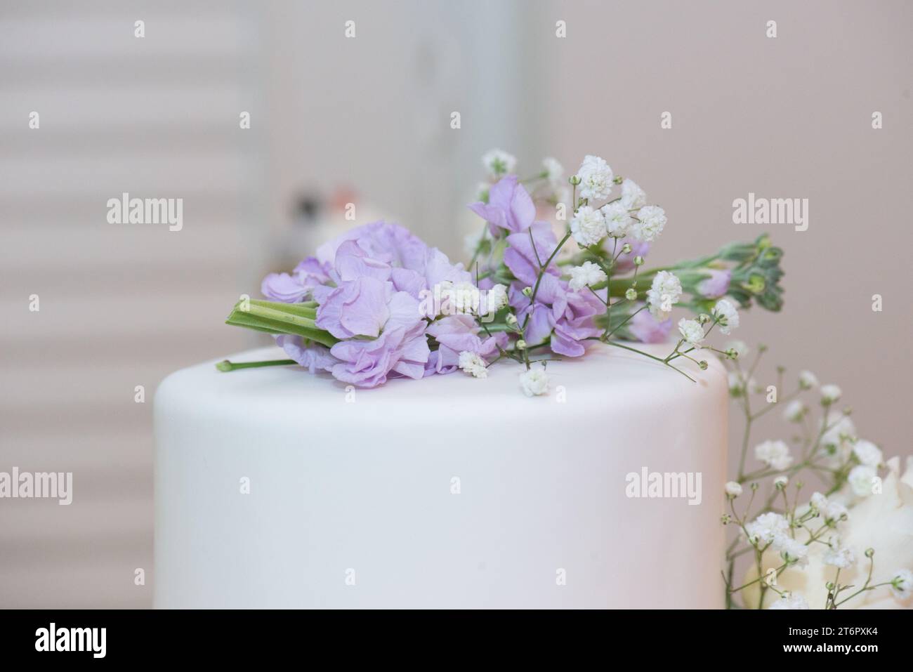 Weiße Hochzeitstorte mit lila Blumenschmuck aus nächster Nähe Stockfoto
