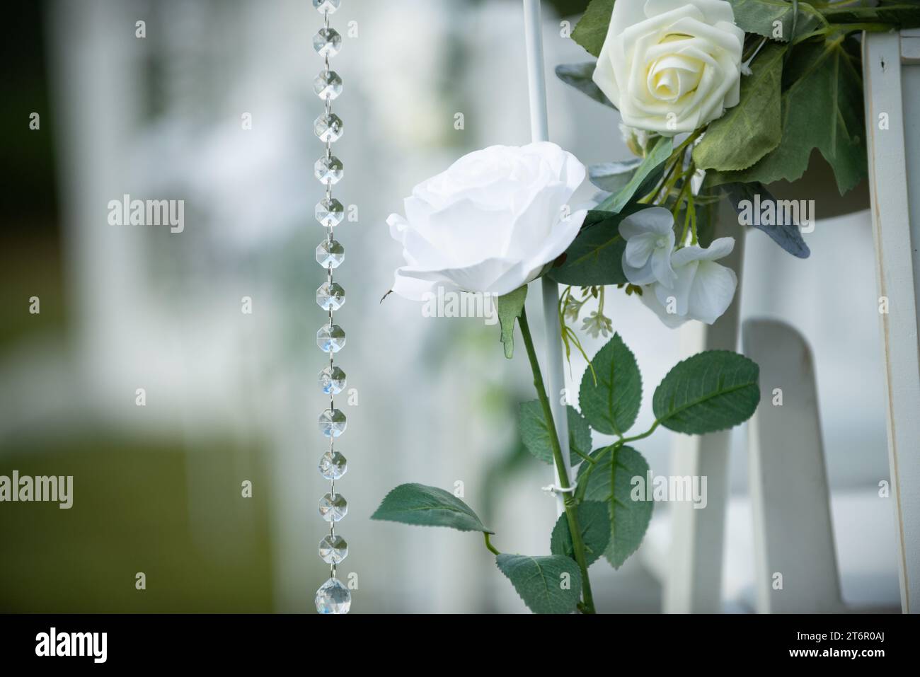 Wunderschöne weiße Rosen mit Kristallen auf weißen Stühlen auf der insel der romantischen Hochzeitszeremonie Stockfoto