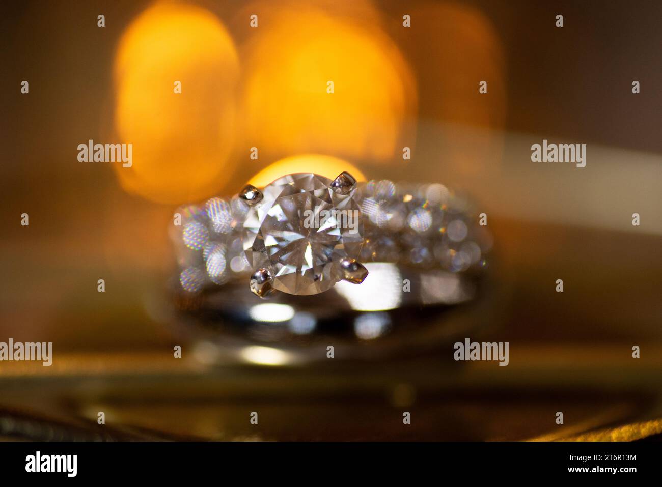 Wunderschöner Diamant-Verlobungsring in warmer Umgebung mit warmem Bokeh und weichem Hintergrund Stockfoto
