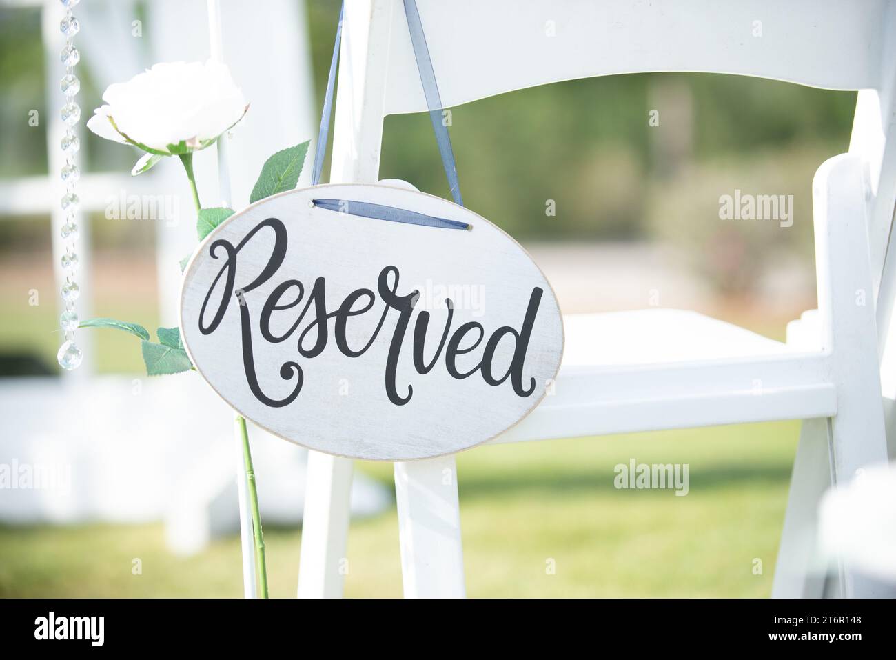 Weißes rundes „reserviertes“ Hochzeitsschild mit schwarzem Text, der am Stuhl auf der insel der Hochzeitszeremonie hängt Stockfoto