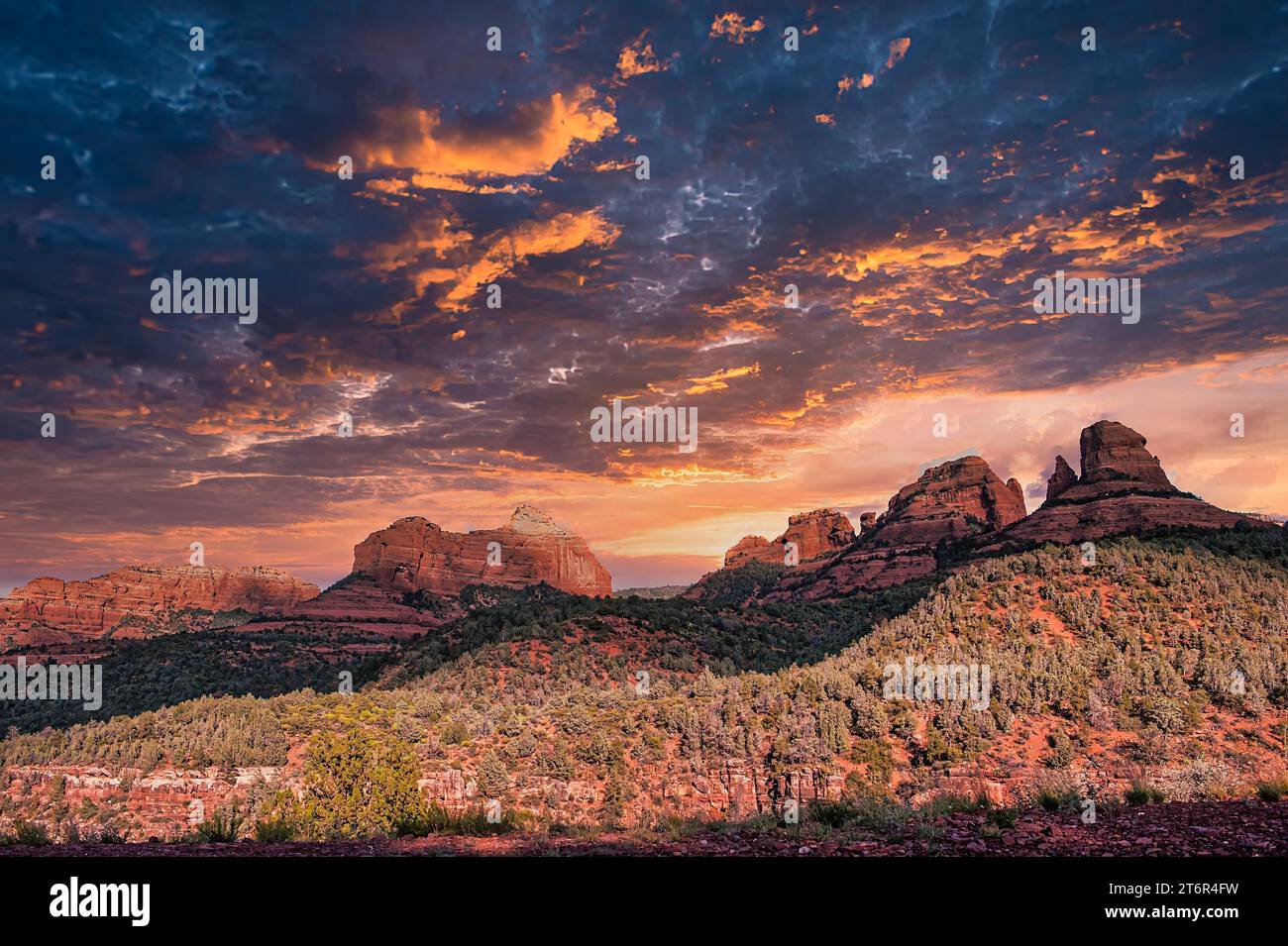 Erleben Sie das atemberaubende Meisterwerk der Natur, während die Sonne anmutig unter den Horizont fällt und ein warmes goldenes Leuchten über die atemberaubende Landschaft von Sedona wirft. Stockfoto