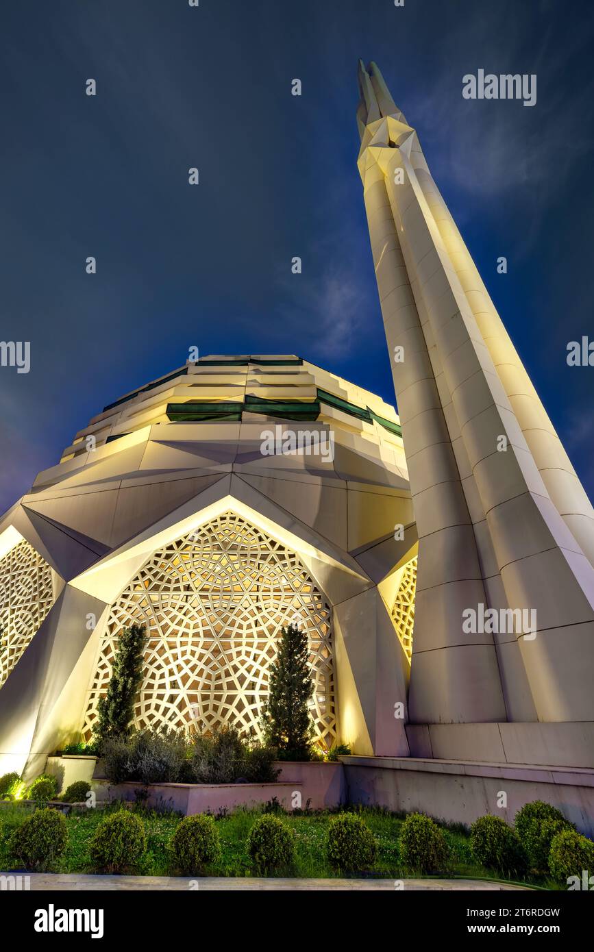 Moschee der Theologischen Fakultät der Universität Marmara, strahlend beleuchtet vor dem Hintergrund eines ruhigen Nachthimmels, mit einem riesigen Minarett, das sich in Richtung Himmel erstreckt, Uskudar, Istanbul, Türkei Stockfoto