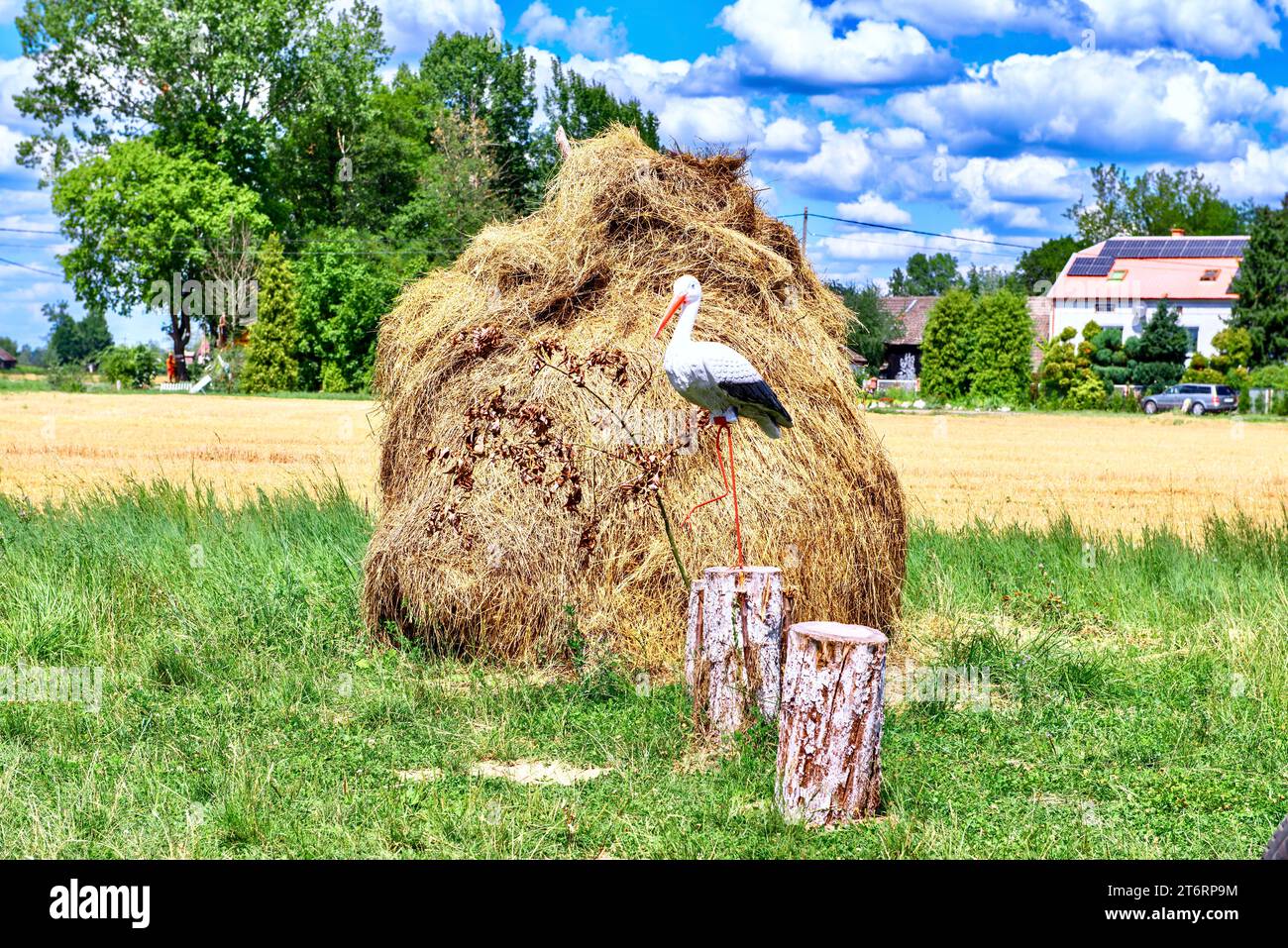 Im Sommer ein Modell eines Storchs auf einem Heuhaufen auf einer Wiese. Stockfoto