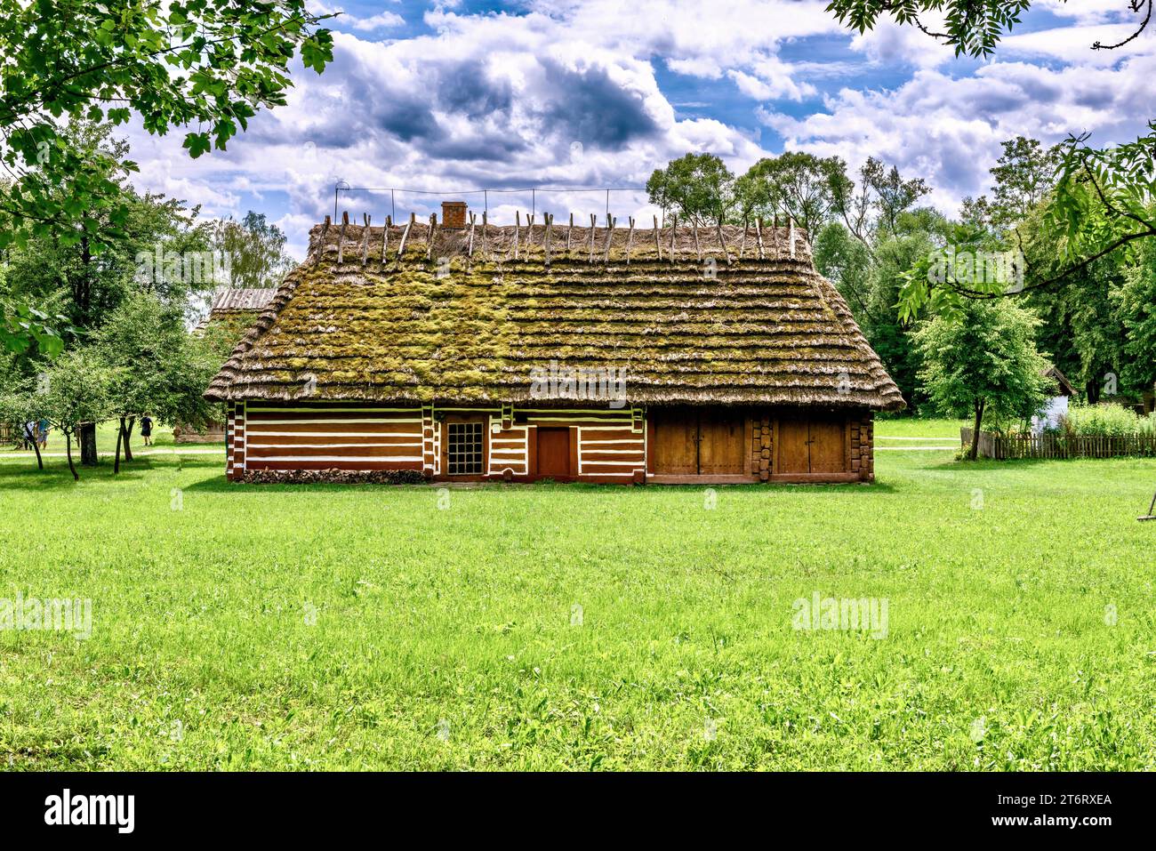 Ein Fragment eines traditionellen polnischen Hauses mit einem Strohdach und einer Holztür im nationalen Stil. Stockfoto