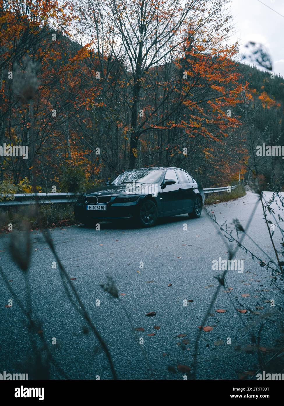 Bulgarien - 11.12.2023: Geparktes Auto auf der Straße mit schönen Herbstfarben im Hintergrund. Stockfoto