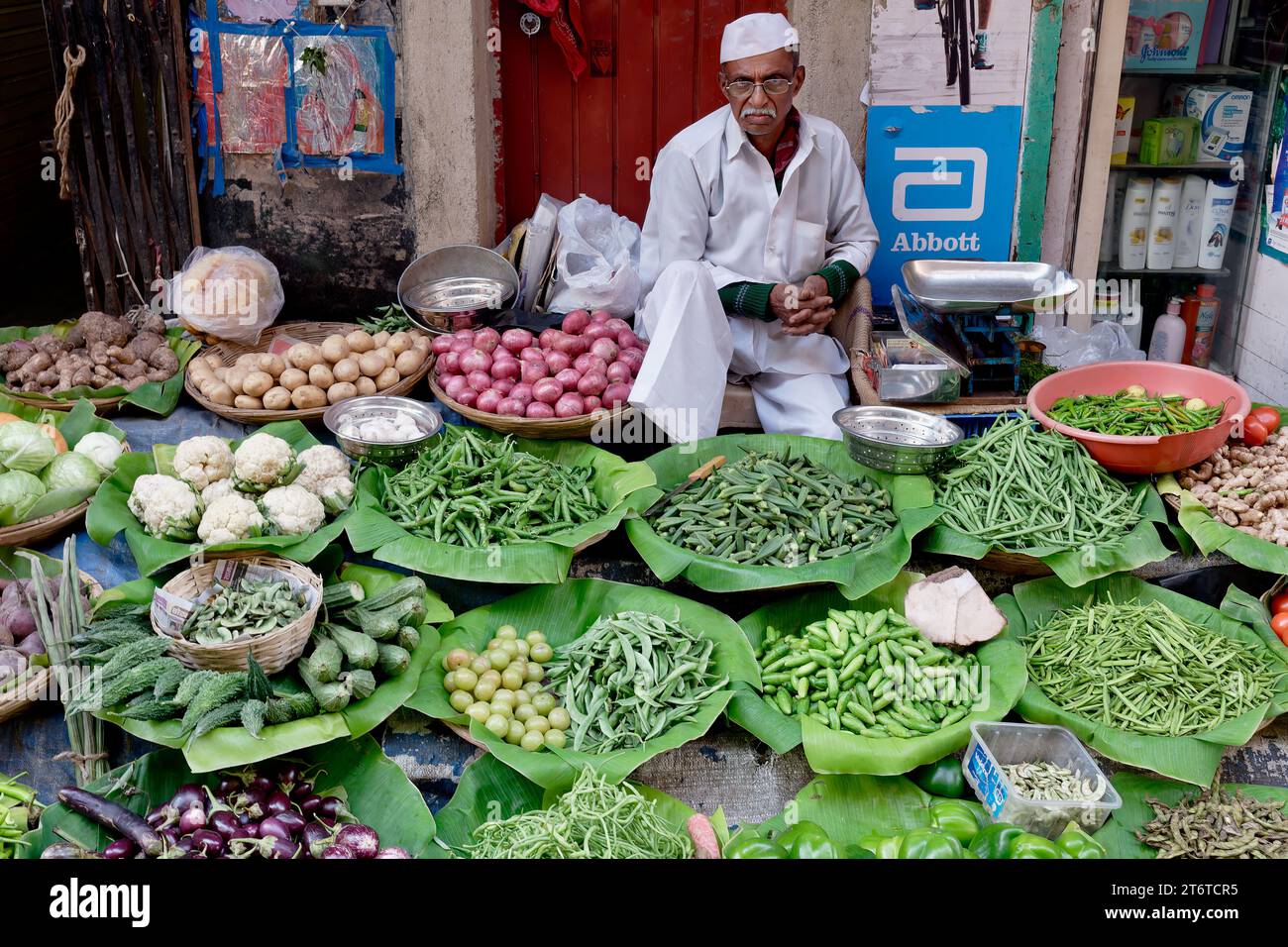 Ein ernsthaft aussehender Maharashtrianer mittleren Alters, der Gemüse auf einem Straßenmarkt in Fort, Mumbai, Maharashtra, Indien verkauft Stockfoto