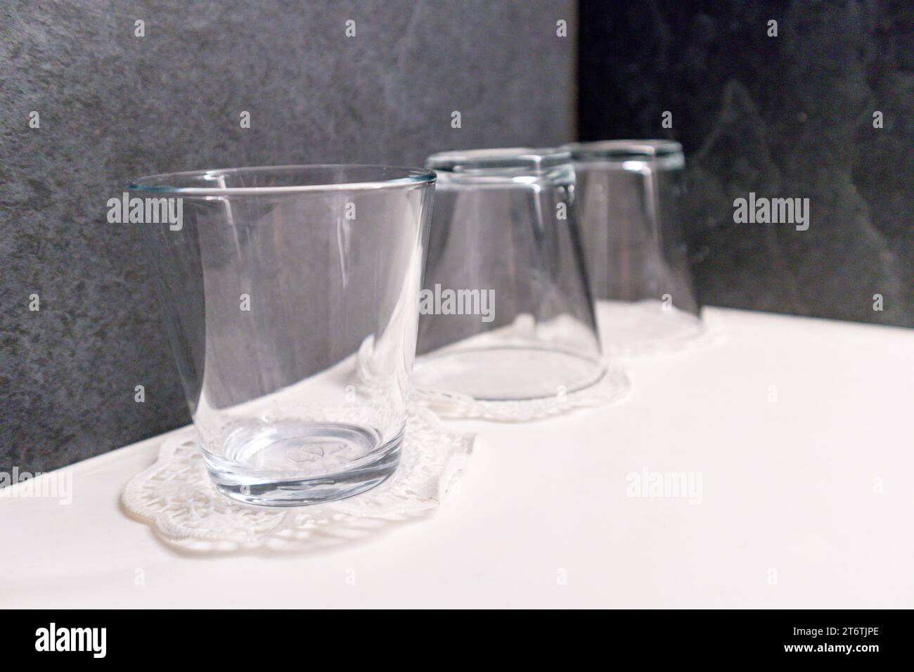 Glasgläser werden nebeneinander am Rand eines weißen Waschbeckens platziert Stockfoto