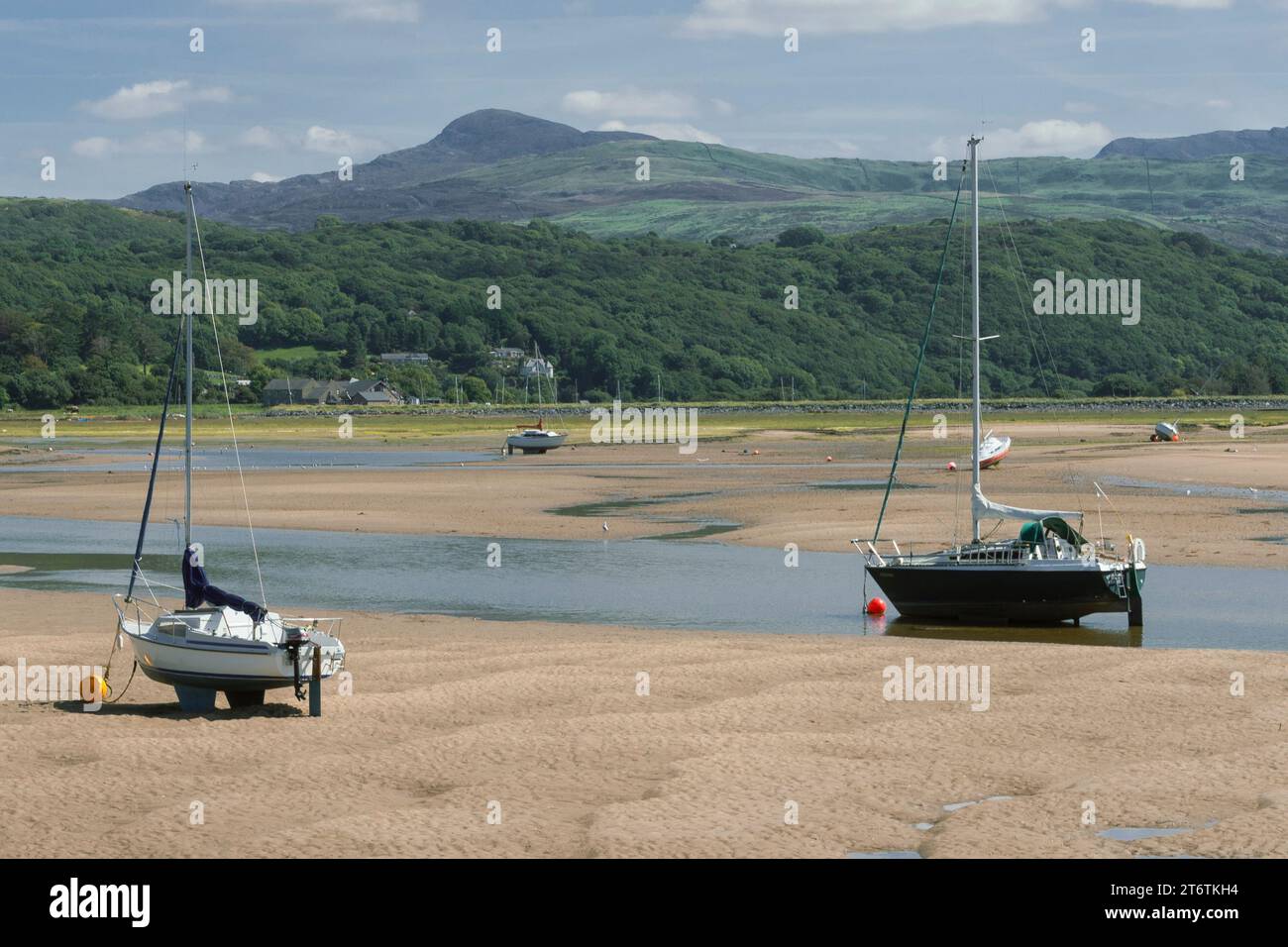 Kleine Segelboote sitzen auf dem Sand und warten auf die Ebbe, die in Abersoch in Westwales im Vereinigten Königreich eintrifft Stockfoto