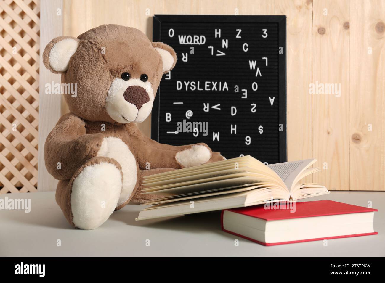 Teddybär, schwarze Brieftafel mit dem Wort Dyslexia und Bücher auf dem Leuchttisch Stockfoto