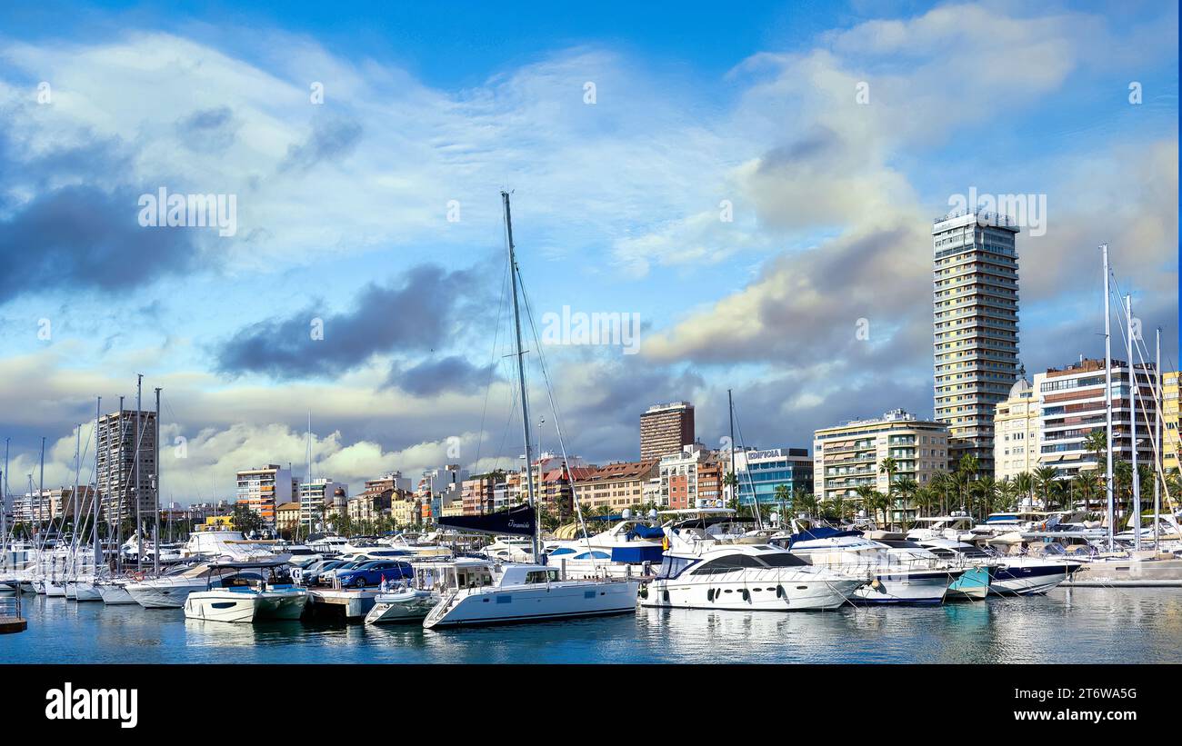 In Alicante, Spanien, liegen moderne Freizeityachten im Yachthafen der Stadt. Ein Winterhimmel mit Blau- und Gelbtönen erleuchtet die Szene. Stockfoto