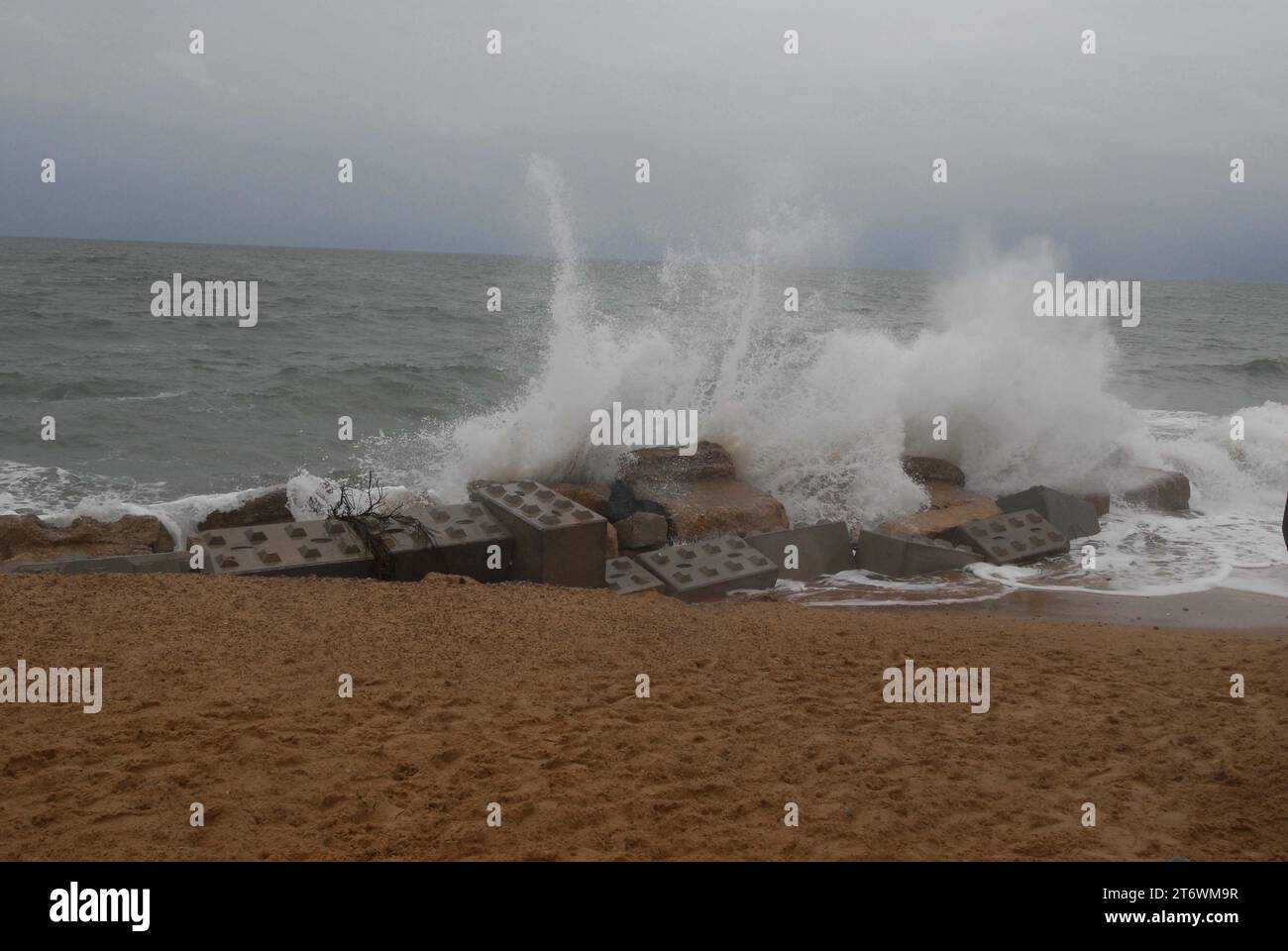 White Sea Spray schießt von großen Wellen auf die Panzerblockflut-Verteidigungsanlagen, die zum Schutz der Zugangsrampe von Hemsby Independent Lifeboat Crew eingesetzt werden. Stockfoto