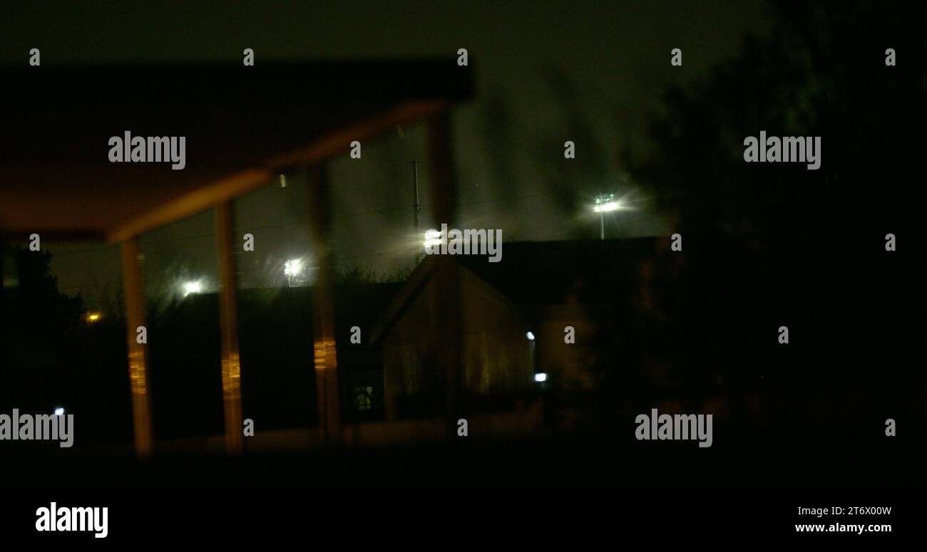 Unheimliche, etwas unheimliche und unheimliche Aussicht auf mächtige Lichter in der Nähe eines Grenzübergangs zwischen den USA und Mexiko vom Hinterhof einer Privatresidenz aus Stockfoto