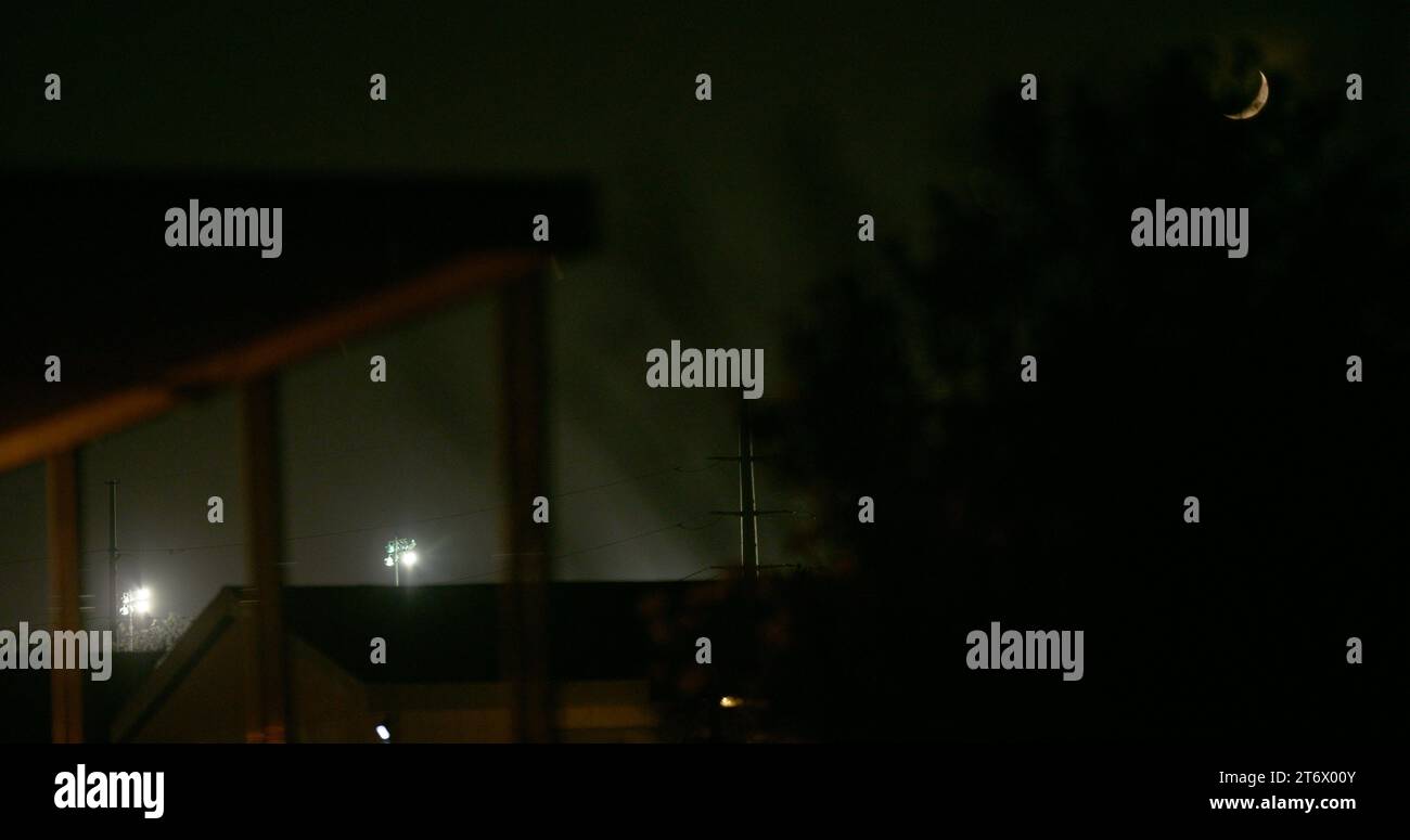 Mondsichel über einem unheimlichen Blick auf die mächtigen Stadionlichter entlang der Grenze zwischen den USA und Mexiko vom Hinterhof einer Privatresidenz aus gesehen. Stockfoto