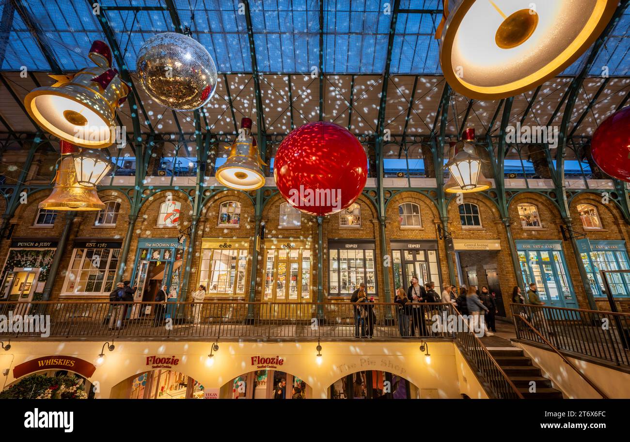 London, UK - 8. November 2023: Covent Garden Market mit Weihnachtsdekoration. Große Glocken und Kugeln hängen vom Dach. Die Leute sind Weihnachtseinkäufe. Stockfoto